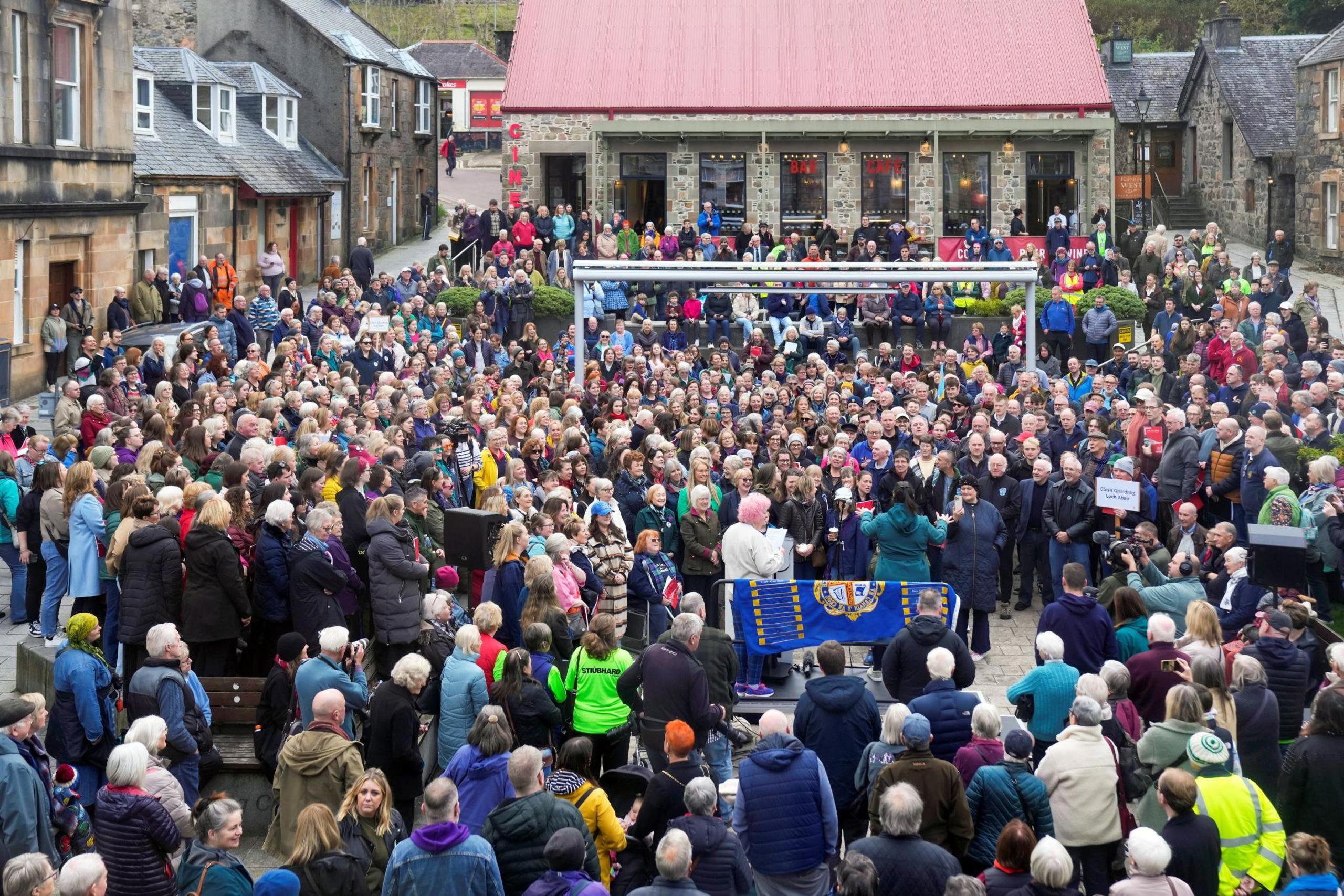 Dozens of people gather to sing Gaelic songs in an open space in Fort William.