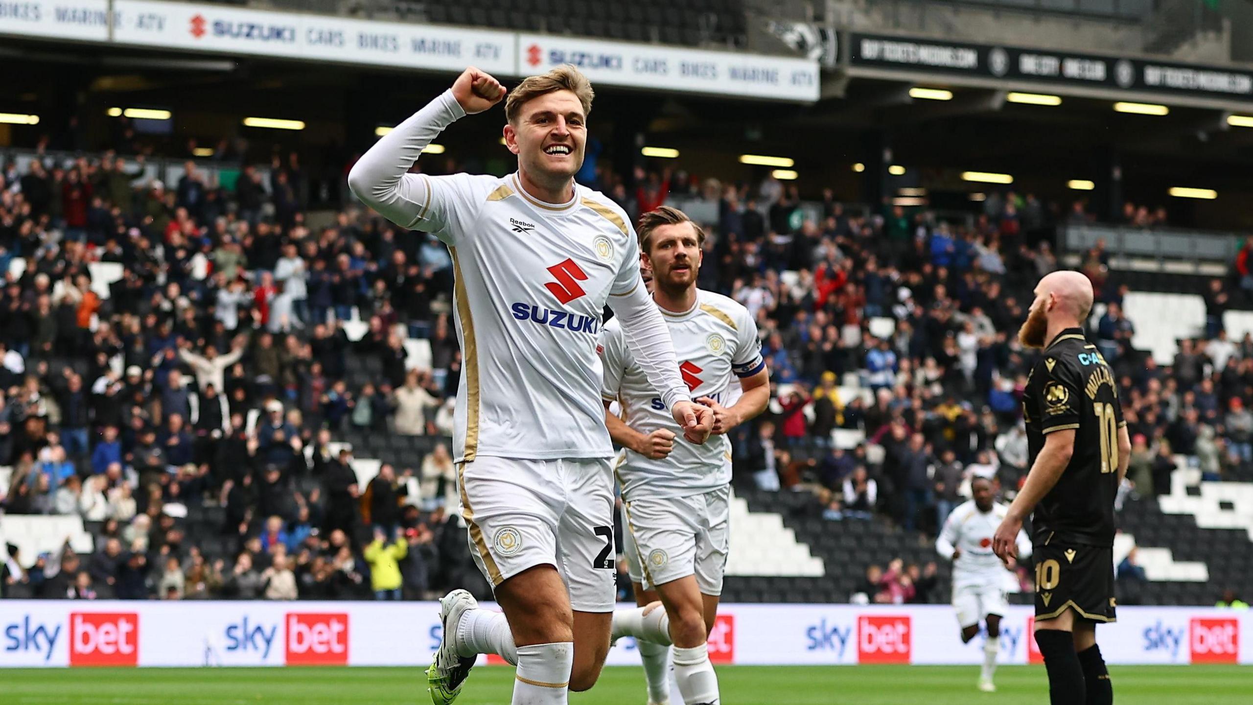 Laurence Macguire runs with his fist in the air after scoring a goal