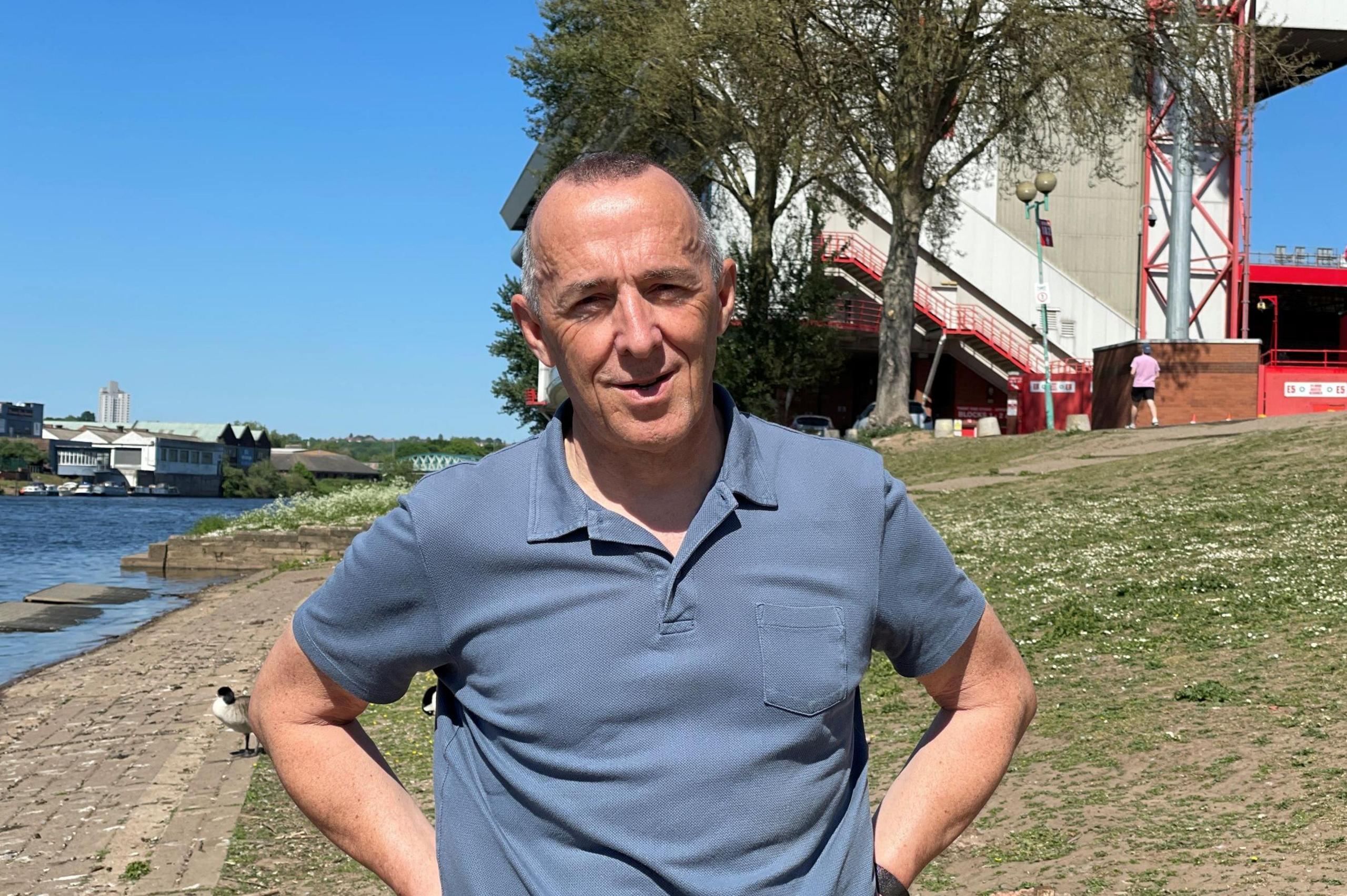 Andy Caddell standing in front of the City Ground, with part of the River Trent visible