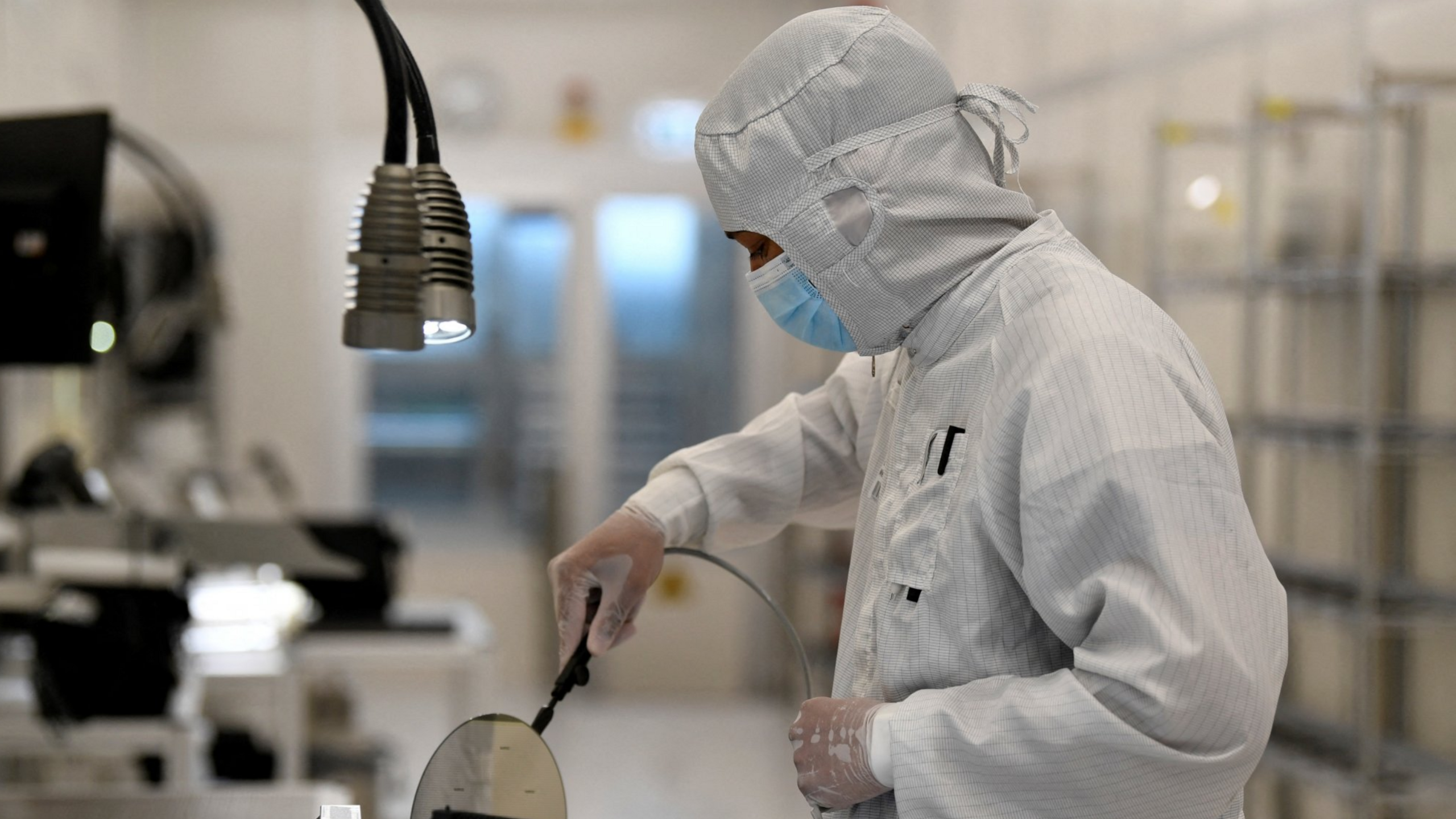 An employee works with a wafer in a production line of Dutch semiconductor company Nexperia, in Hamburg, Germany.