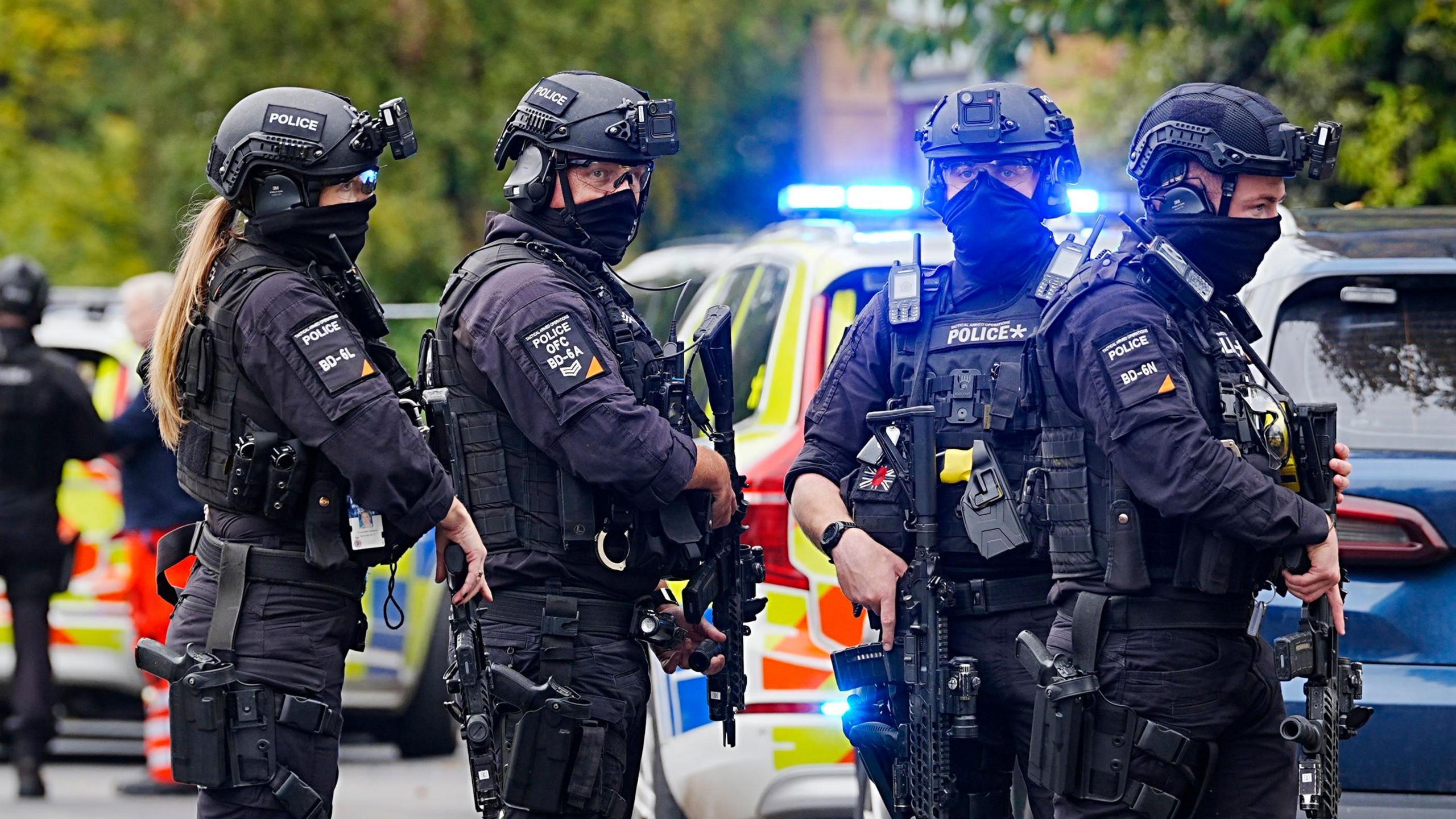 Armed police officers at the scene near the Heaton Park Hebrew Congregation synagogue in Crumpsall, Manchester, where two people died in a suspected terror attack by a man who was shot dead by police. The four officers are dressed in black, holding assault rifles and wearing helmets with face coverings drawn up over their mouths. 