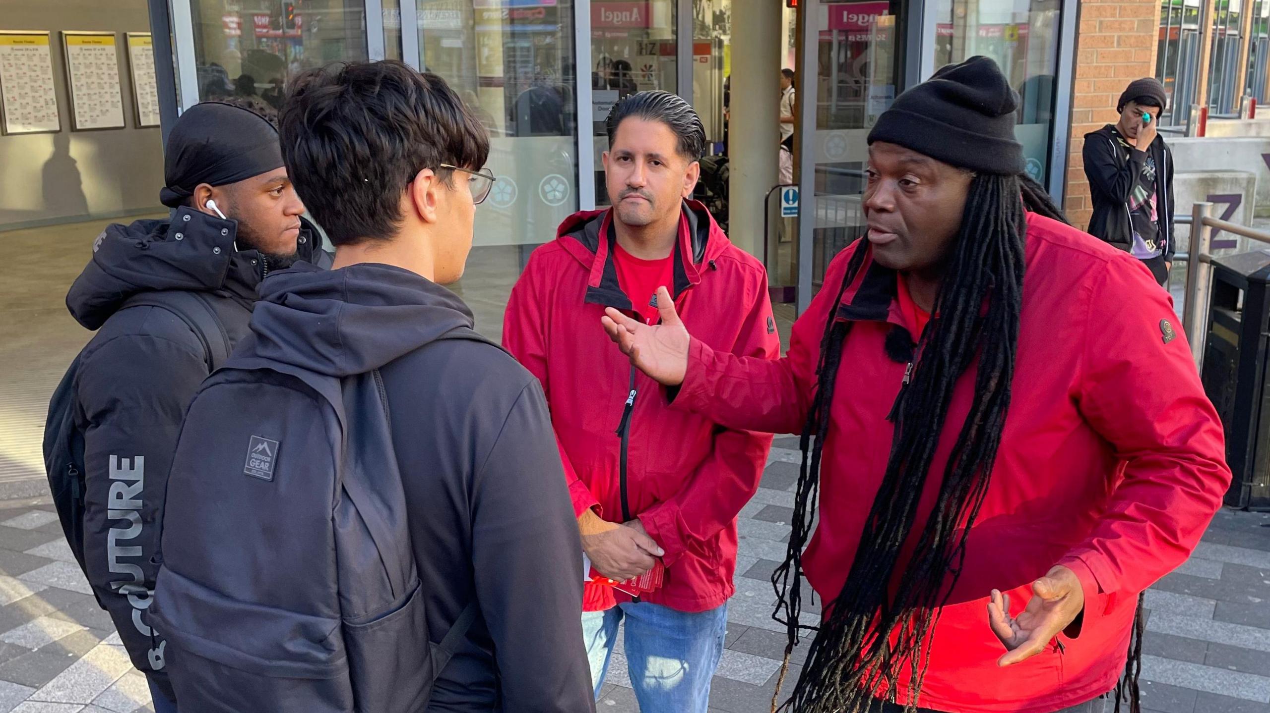 The street outreach team talk to two college students outside the bus station