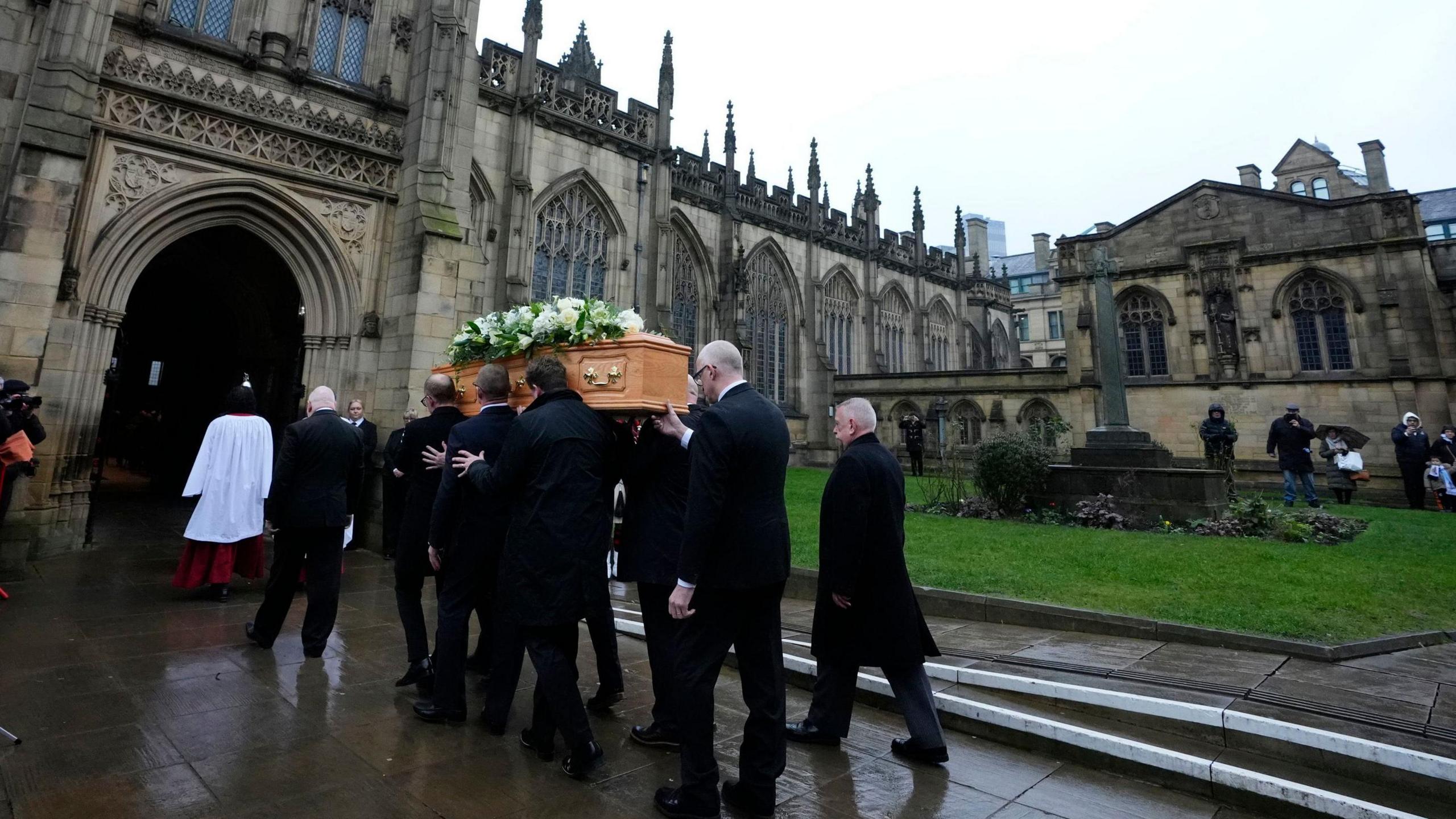 The coffin of Denis Law is carried into Manchester Cathedral.