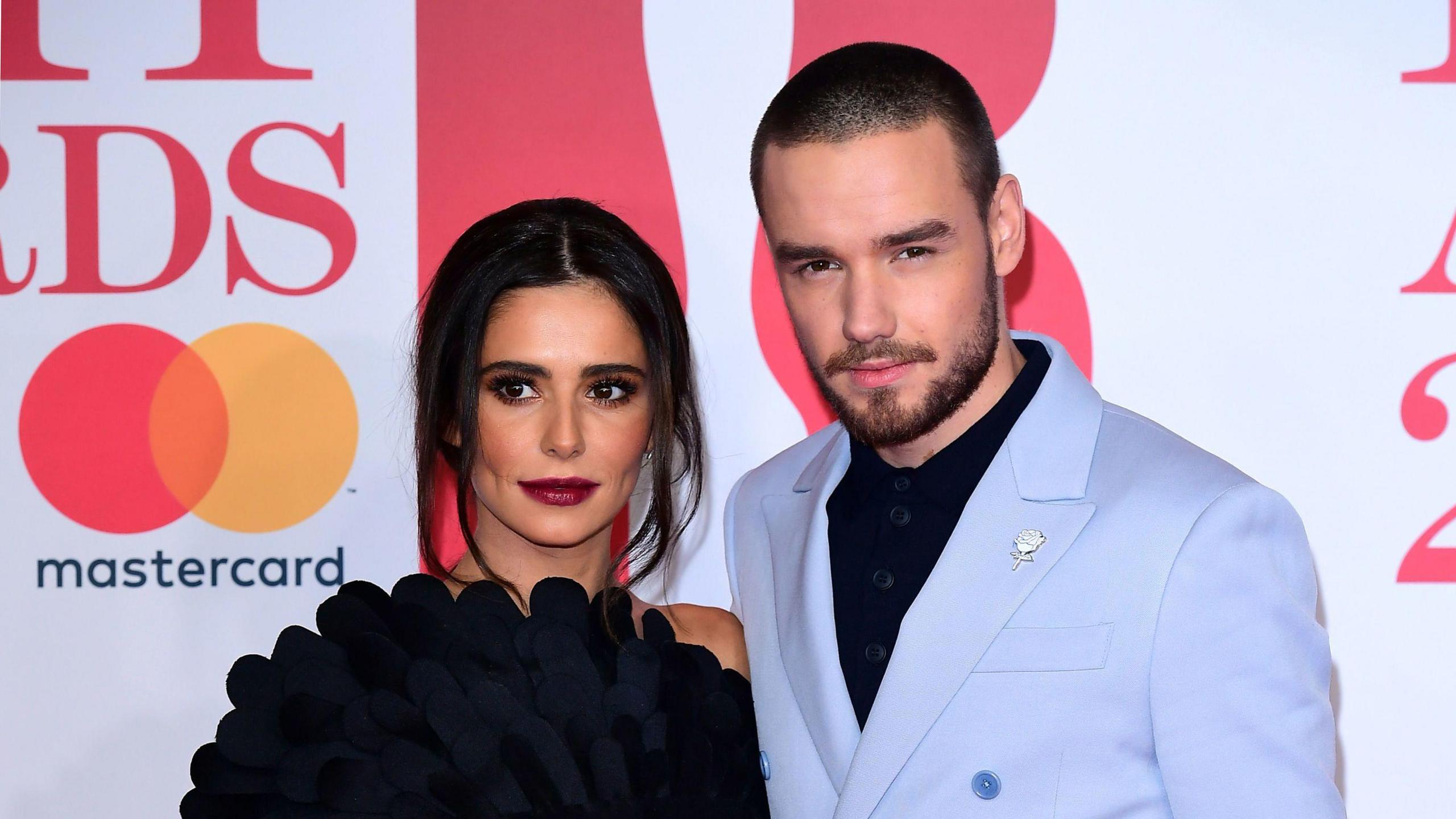 A woman and man stand next to each other at a red carpet event