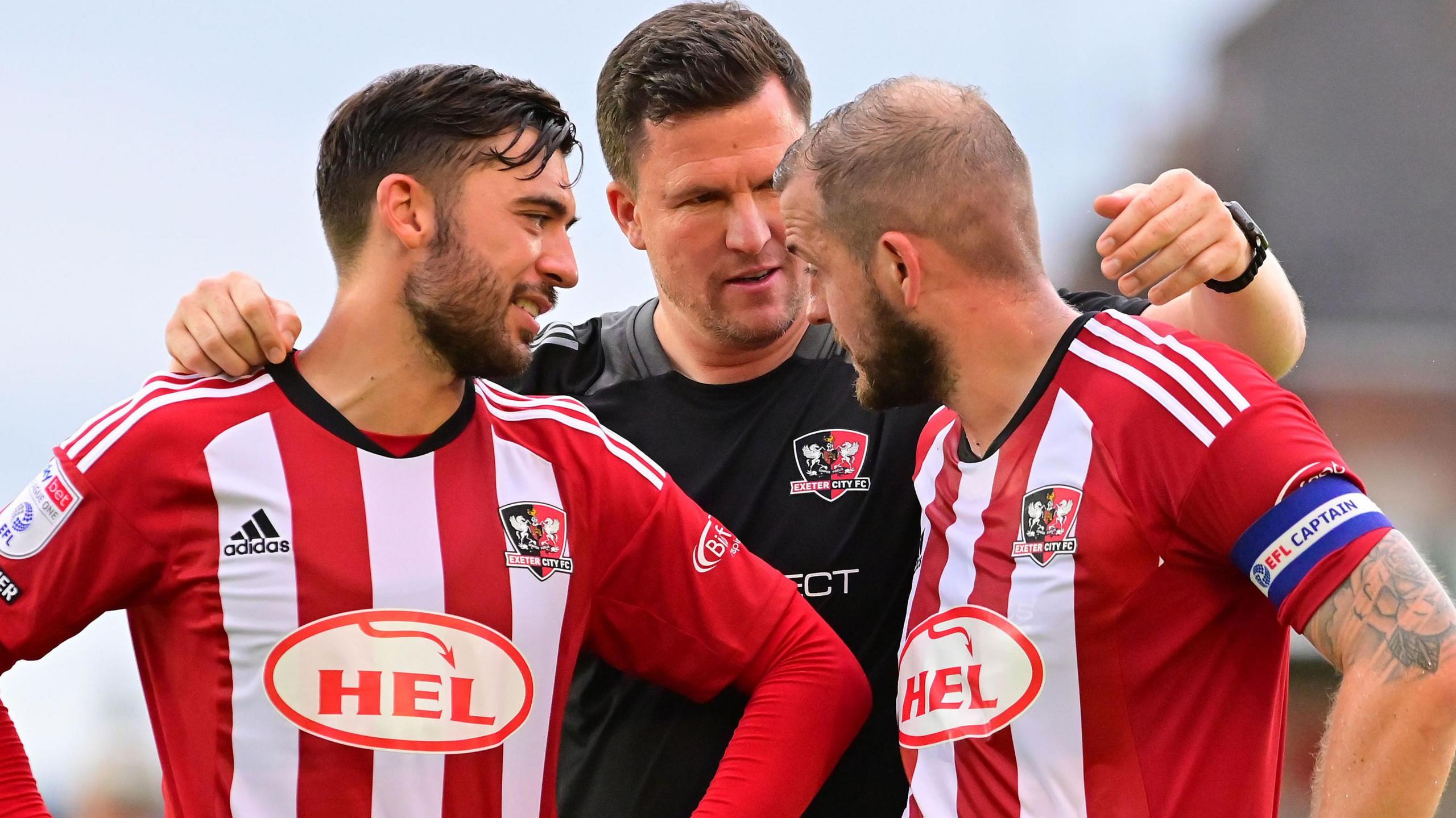 Gary Caldwell puts his arm around Exeter players