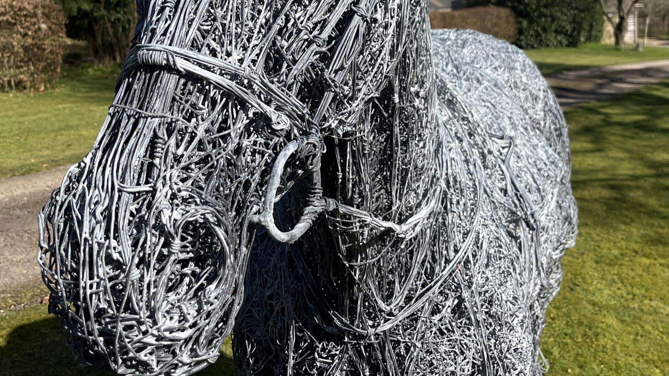 A close up view of the horse sculpture's face and neck area. It shows the intricate wire wrapping forming the horse's bridle and reins. 