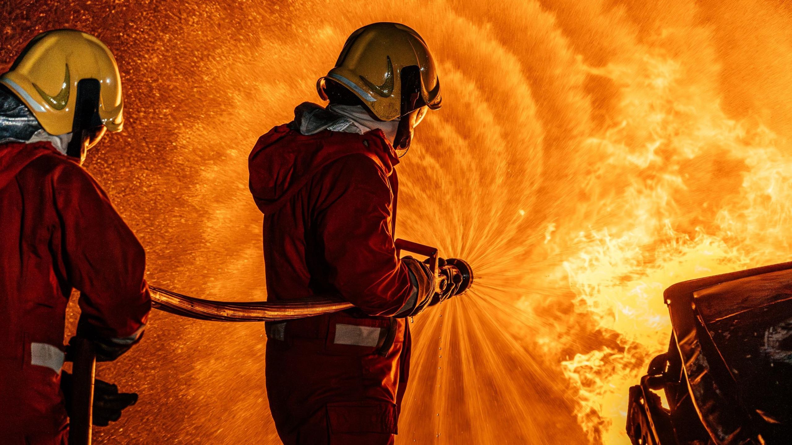 Firefighters spray water on a fierce fire