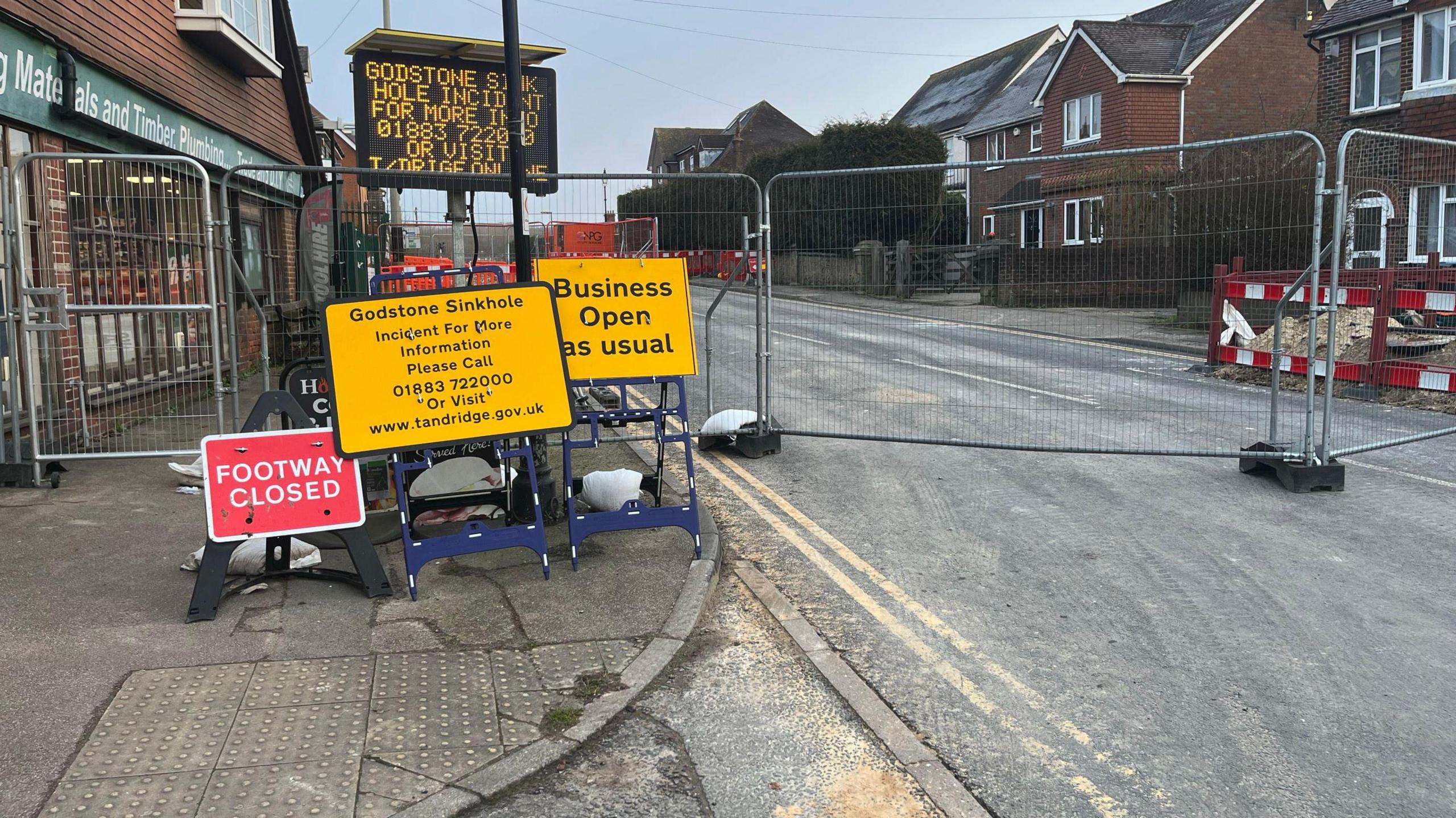 Road signs at a closed road in Godstone, with one stating that businesses are open as usual.