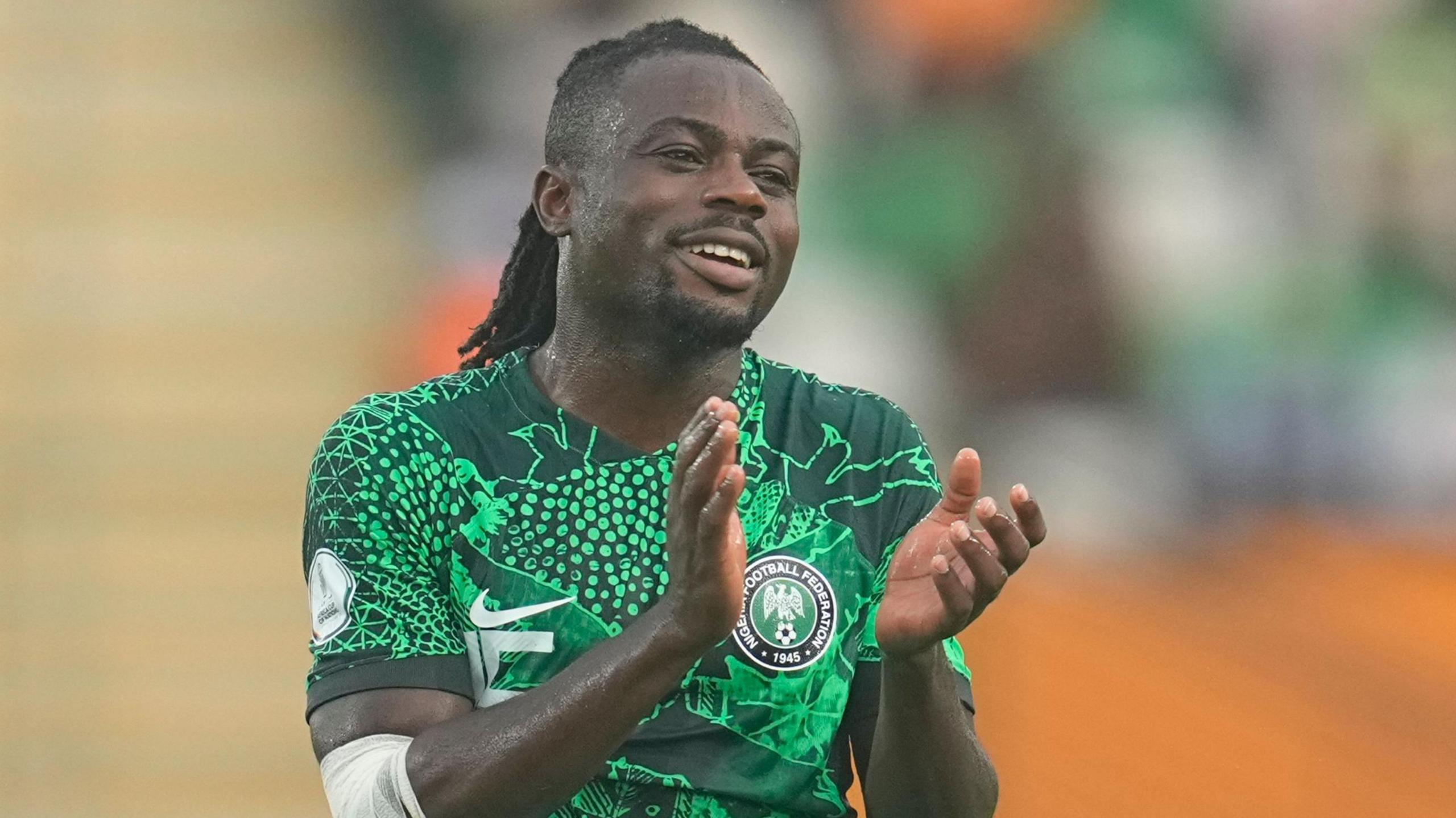 Moses Simon, wearing a green Nigeria shirt, applauds after a game