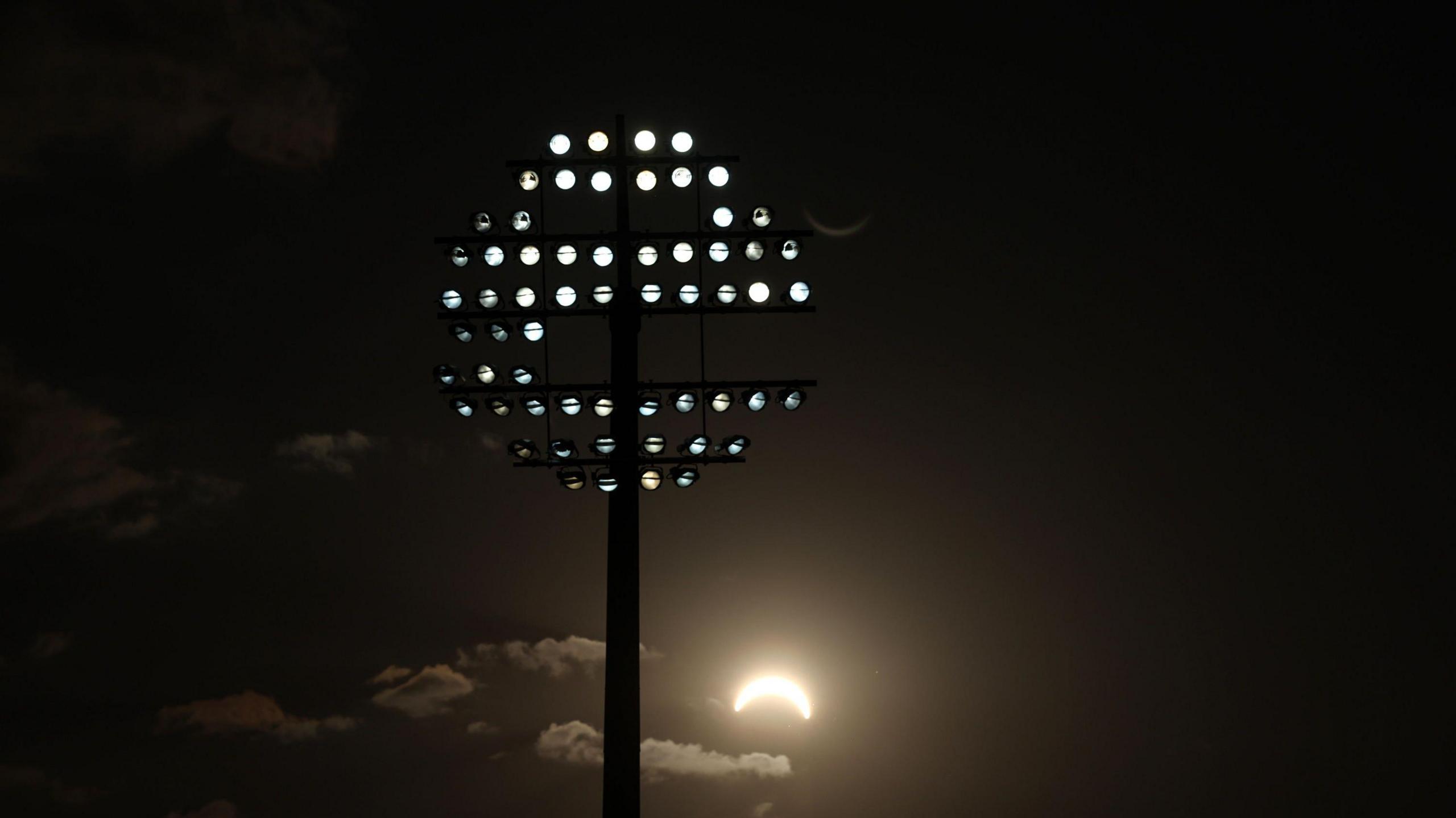 The solar eclipse is seen behind the floodlights at Edgbaston during the men's Hundred match between Birmingham Phoenix and MI London