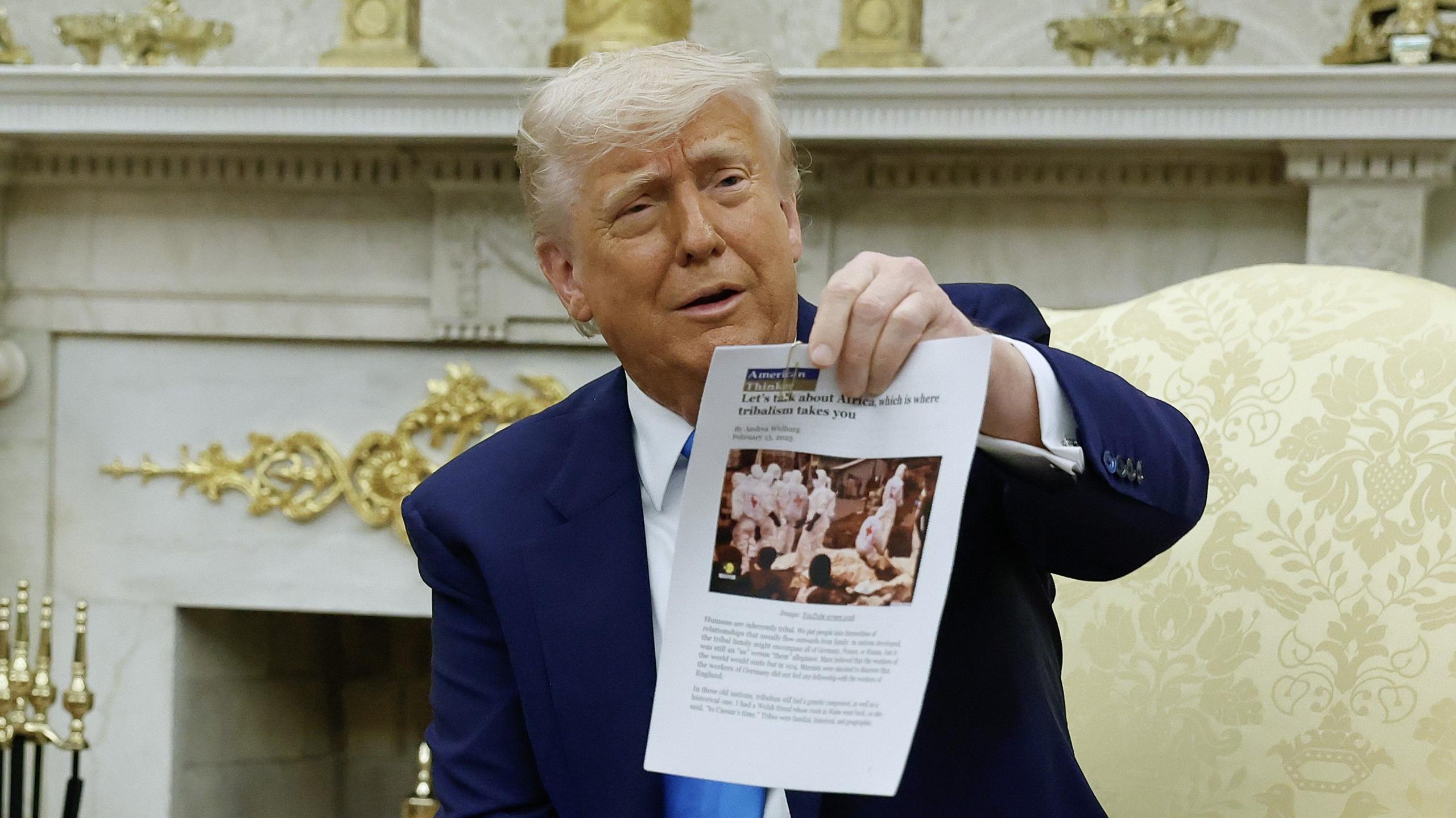 U.S. President Donald Trump holds up a printed article from "American Thinker" while accusing South Africa President Cyril Ramaphosa of state-sanctioned violence against white farmers in South Africa