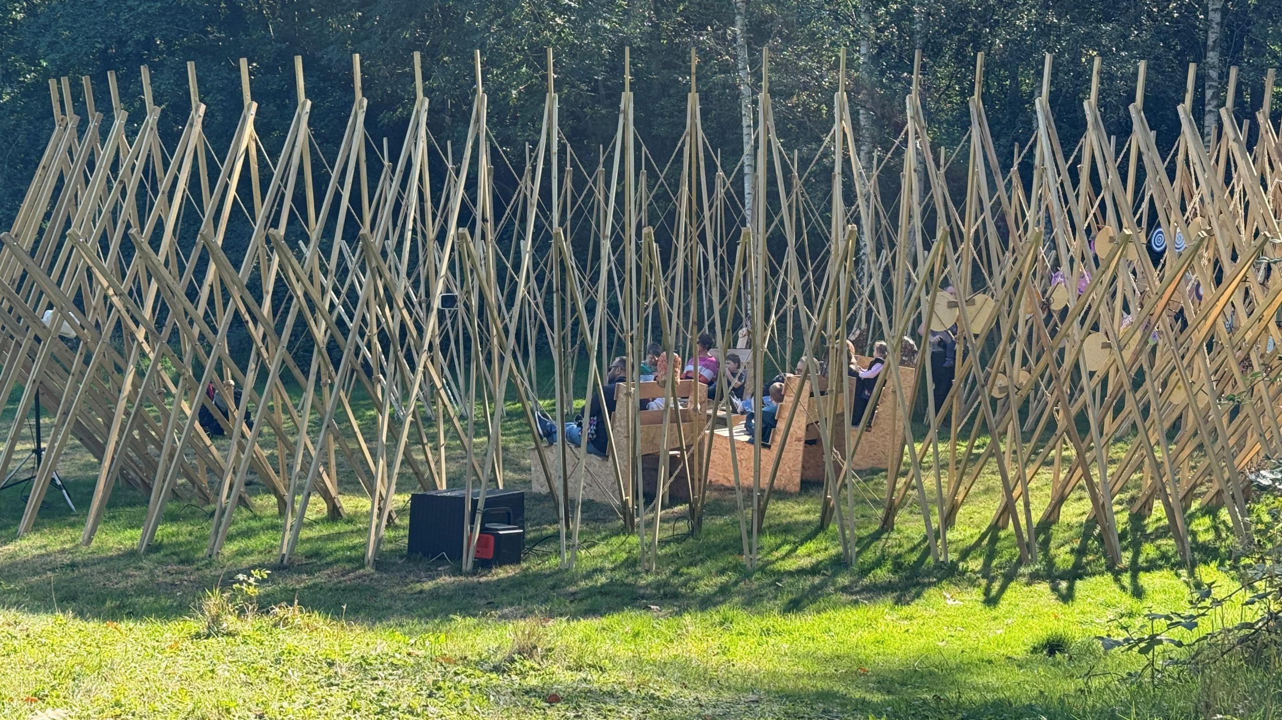 A circular wooden structure with benches inside, where children are seated and interacting.