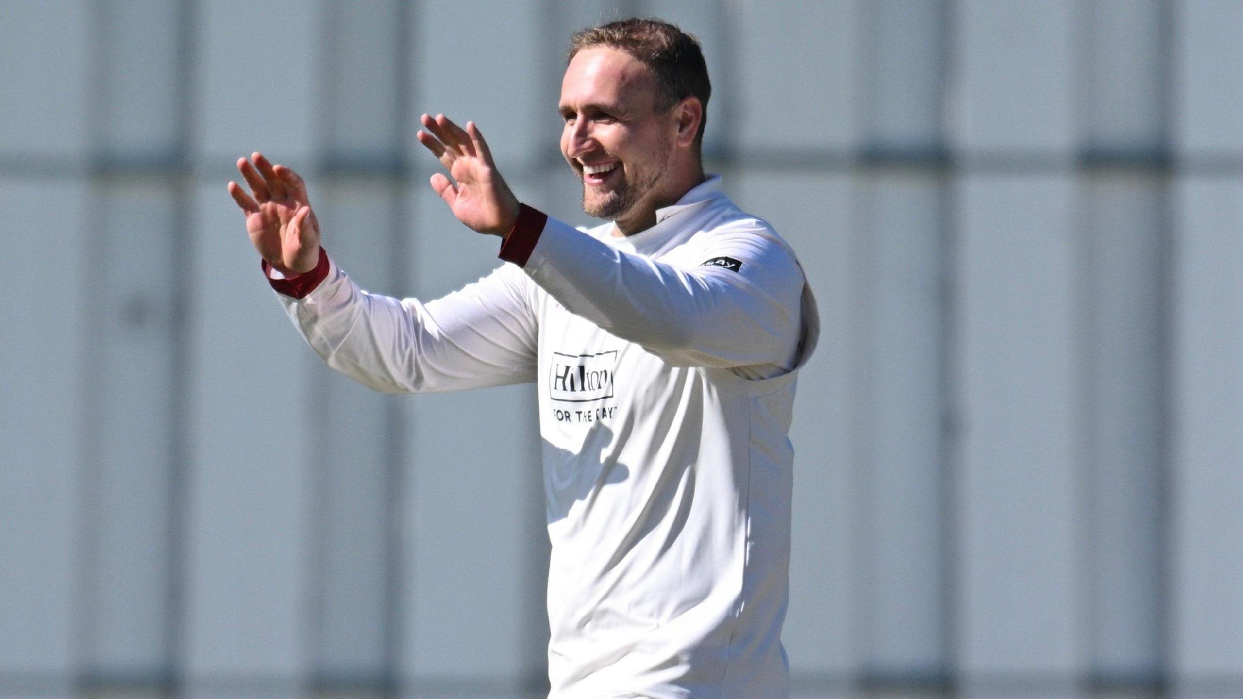 Liam Livingstone, wearing Lancashire cricket whites, celebrates with his hands held up to give a high-five and a smile on his face after taking a wicket against Kent