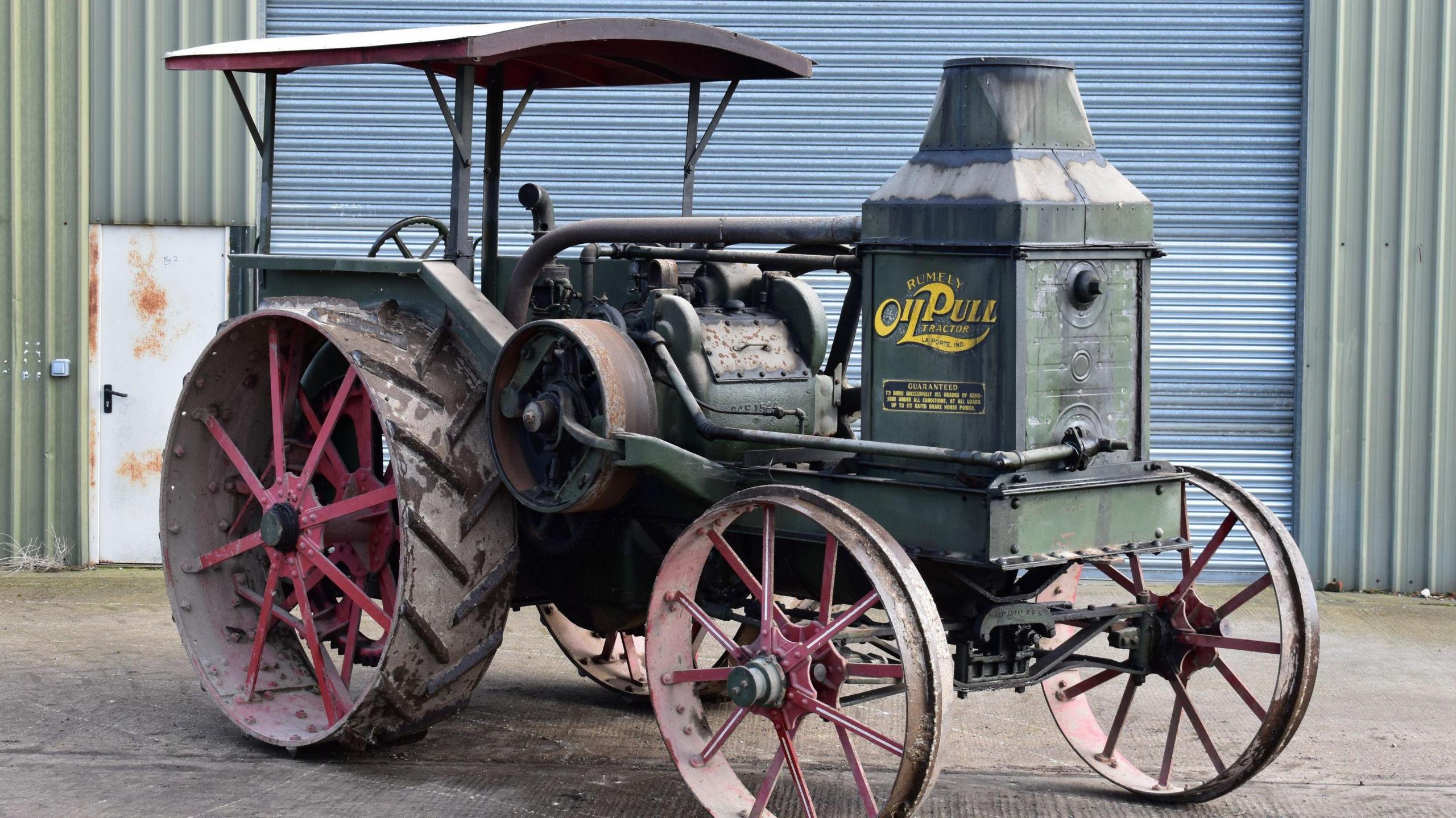 A 1917 Rumely Oil Pull tractor parked in front of a warehouse-type building.