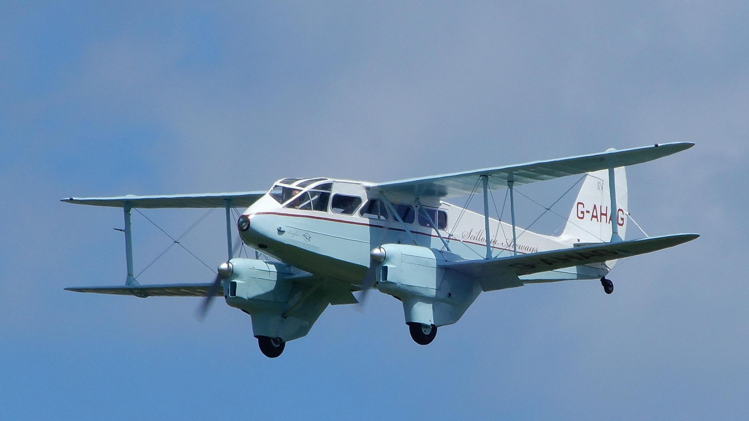 A twin-engine wooden biplane on a cloud-free sky.