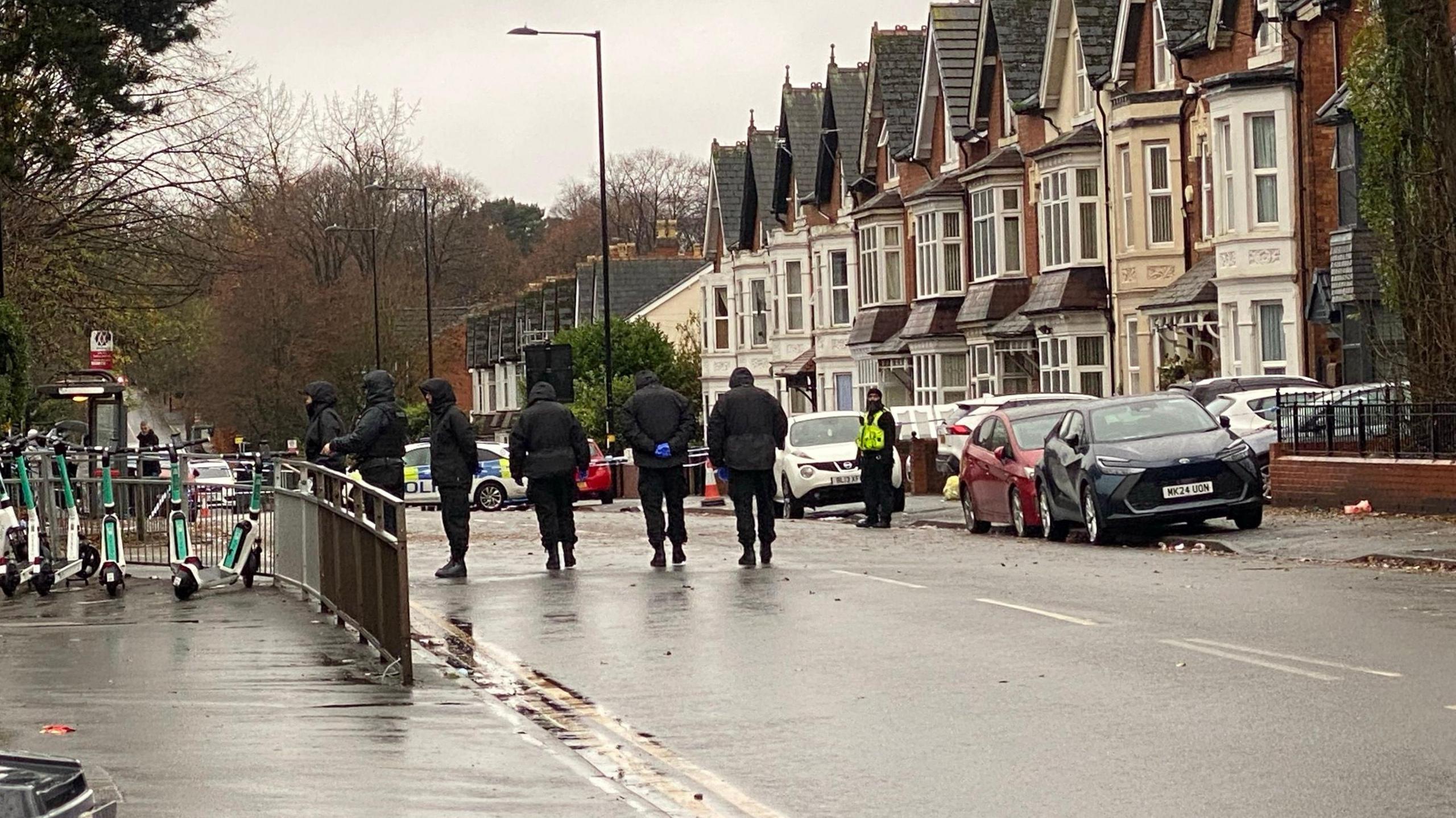 Six officers in black clothing walk in a line up the road