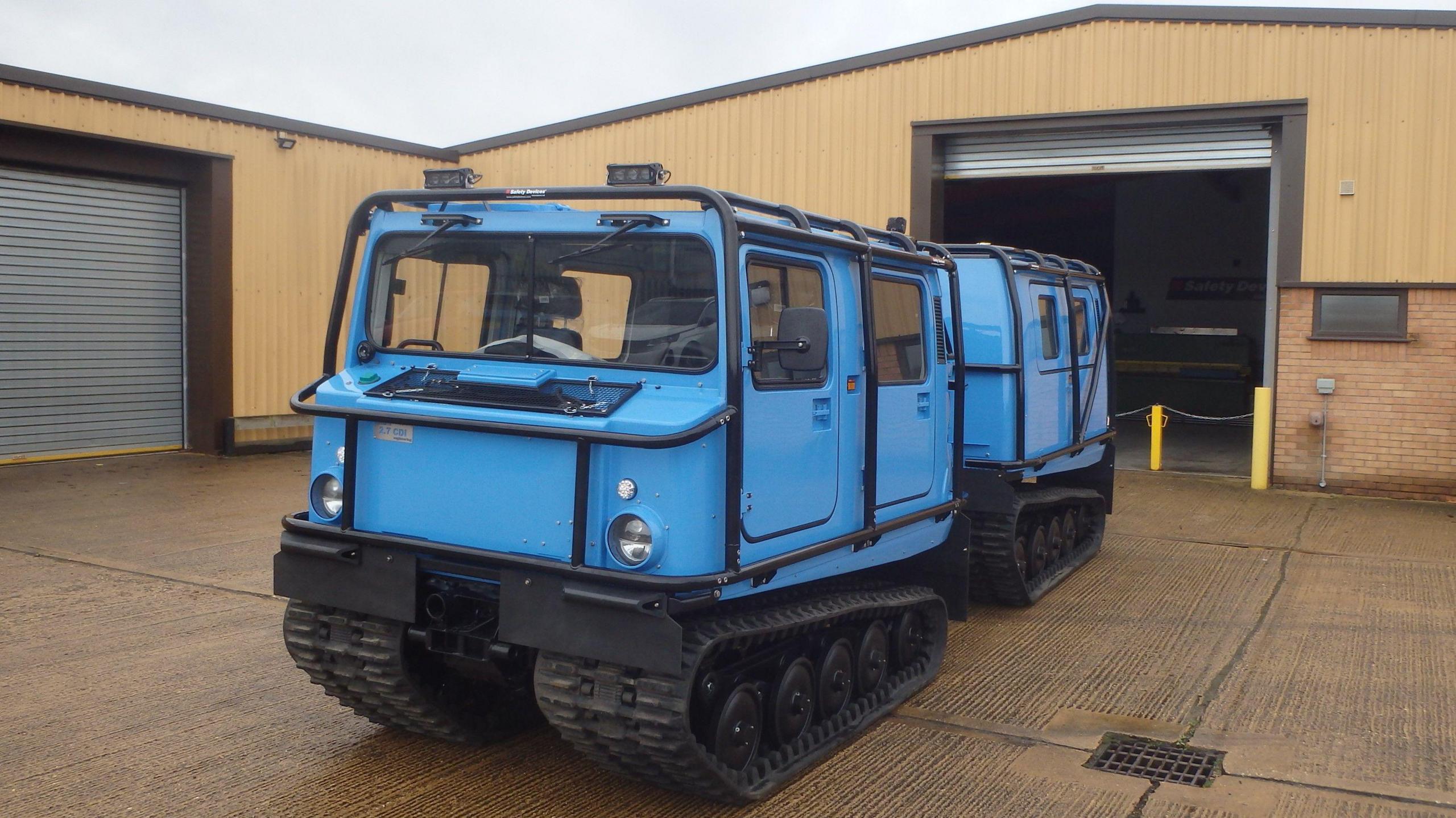 A blue amphibious vehicle with two cabins and on tracks