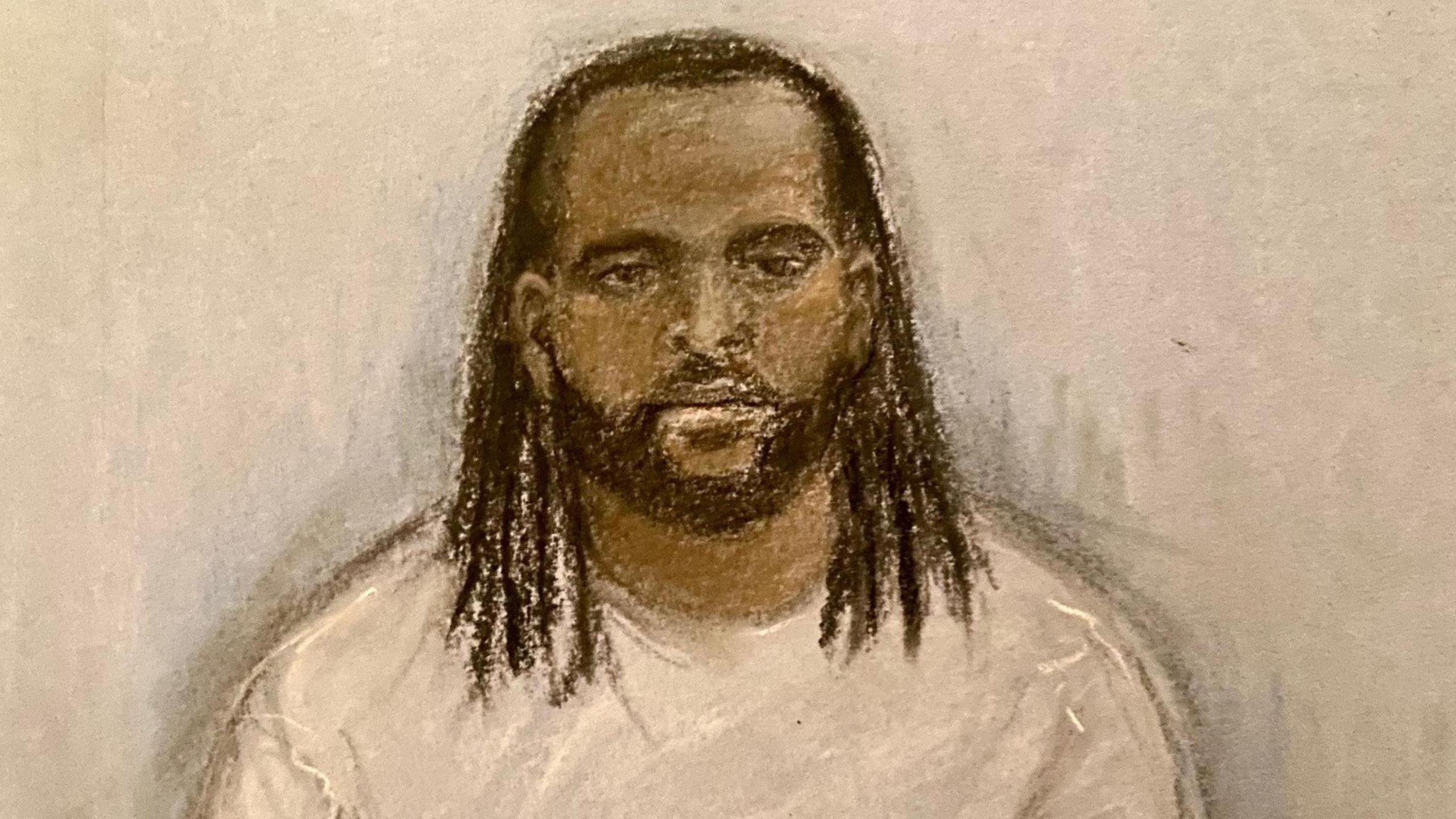 A court sketch of Jay Emmanuel-Thomas. He has long, black hair and a beard. He is wearing a grey sweater and looking forwards with no expression.