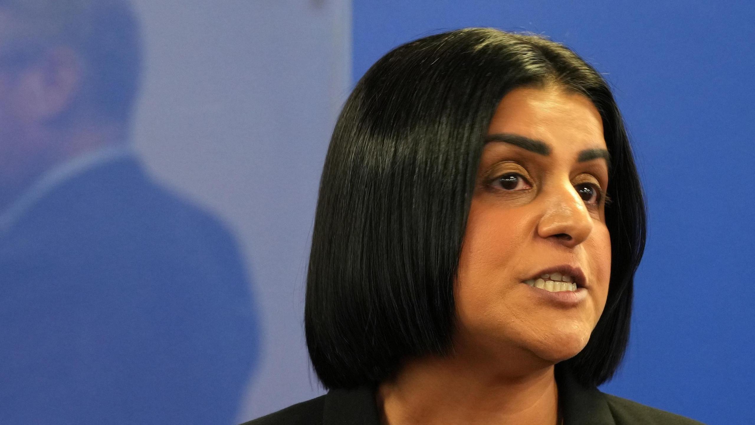 Shabana Mahmood, a woman with dark hair in a bob, speaking against a pale blue background