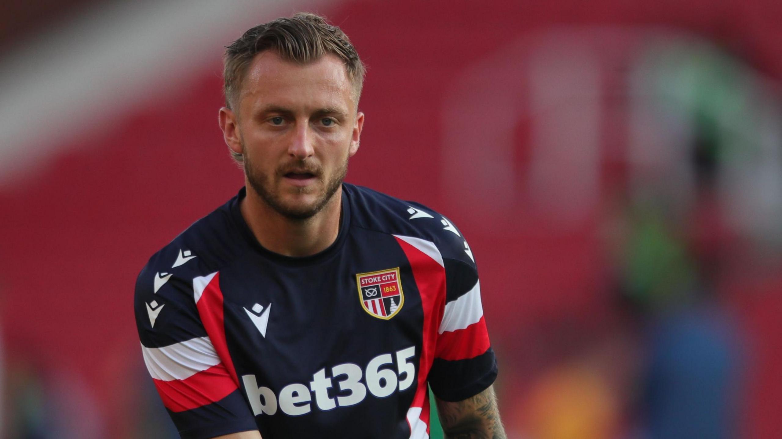 Ben Wilmot in action for Stoke. He is wearing the club's third kit of navy blue with red and white hoops on the sleeves.