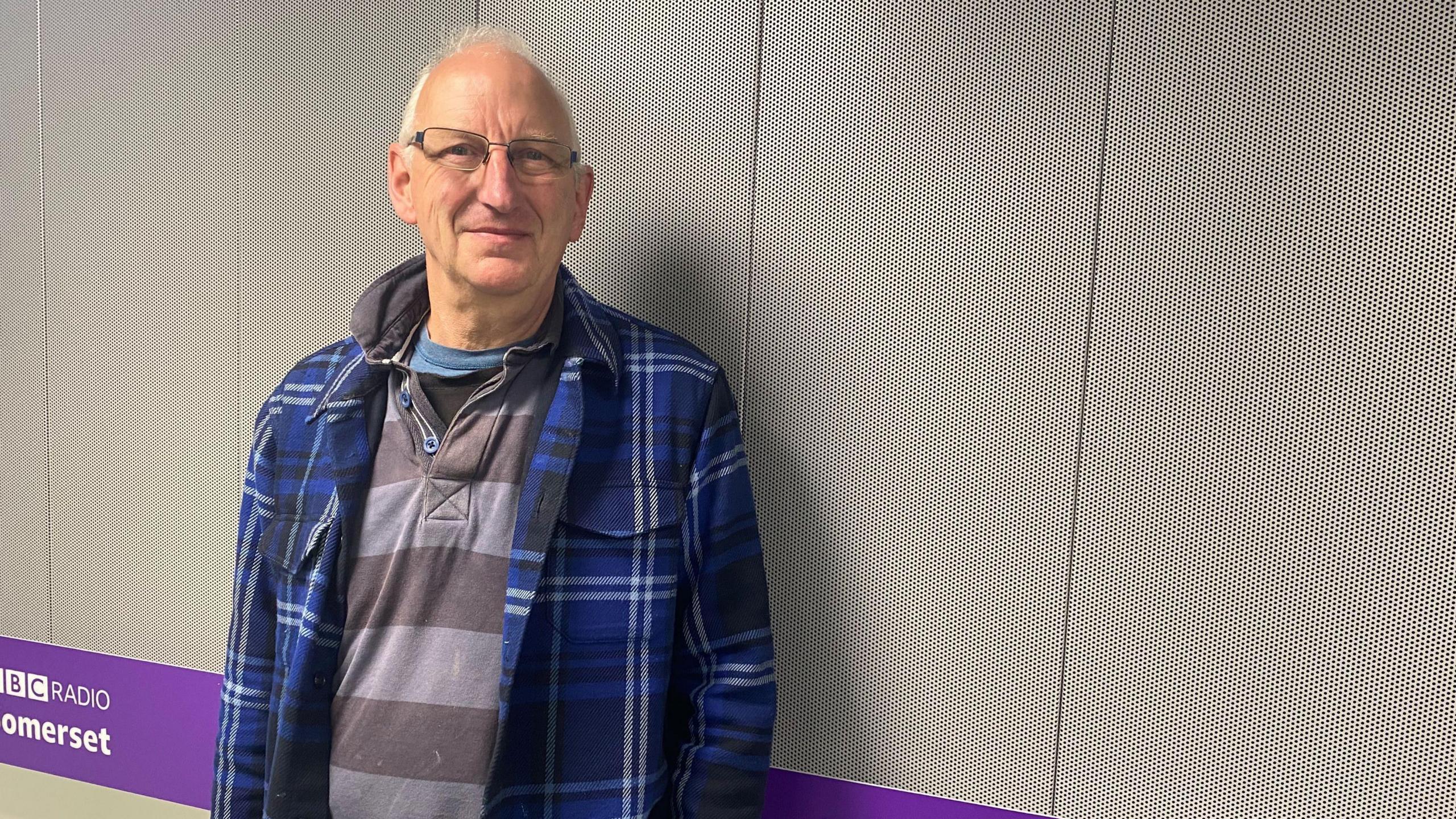 Justin Adams in a blue shirt standing in a BBC Somerset studio