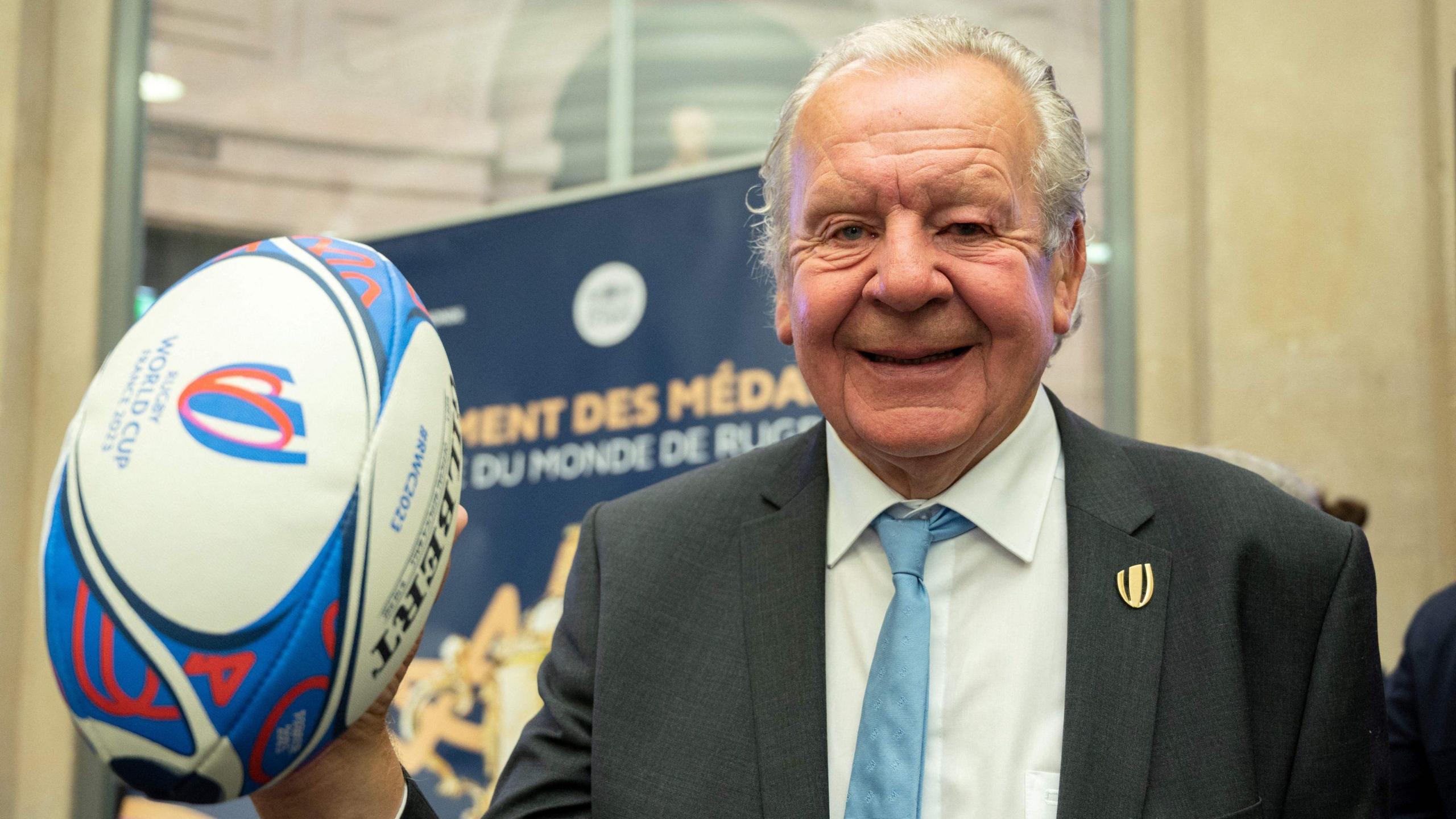 World Rugby chair Sir Bill Beaumont holds up a rugby ball at a press conference for the 2023 World Cup