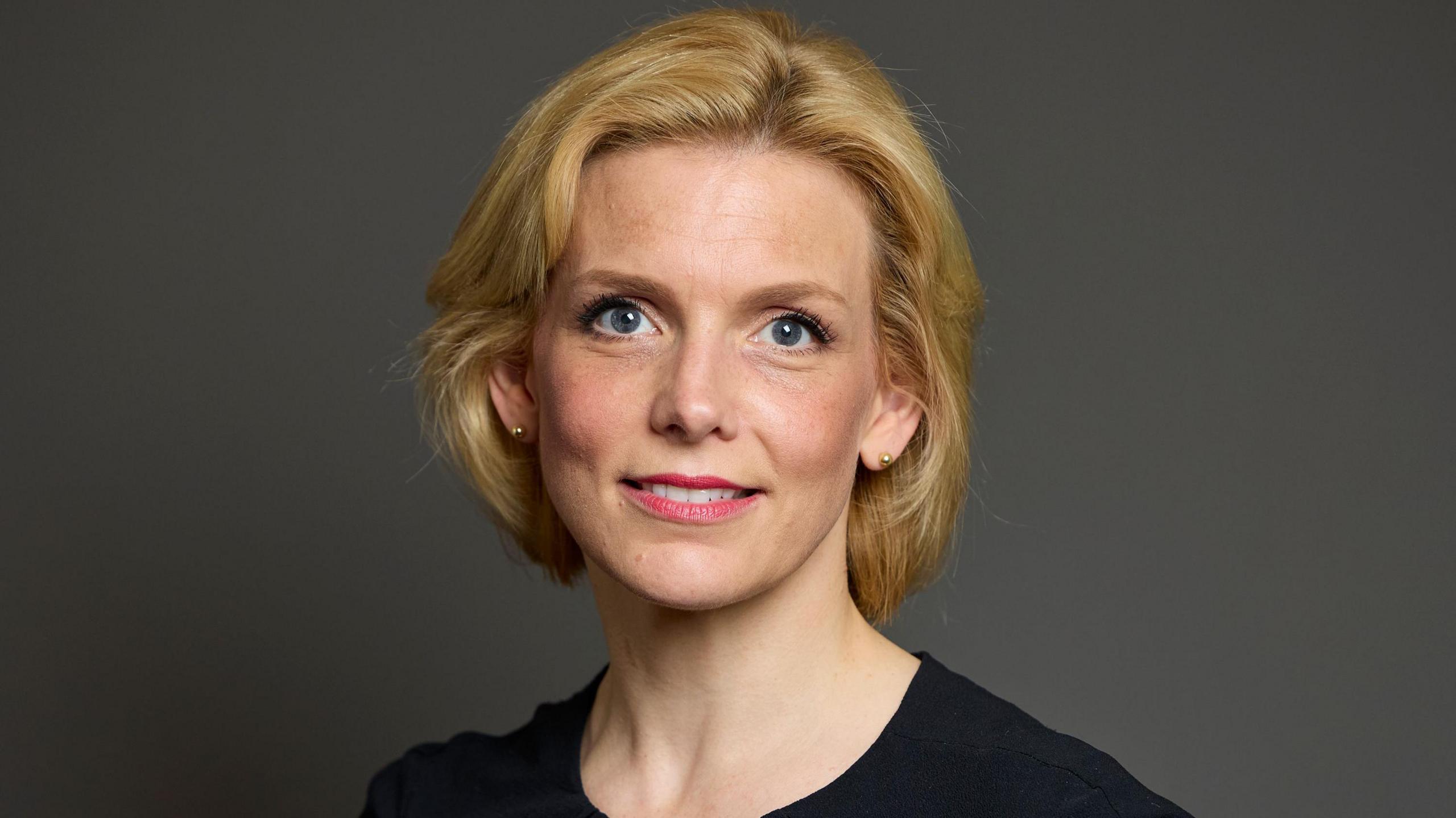 Parliamentary Portrait of Samantha Niblett. She has a blonde bob haircut and is wearing a black dress.