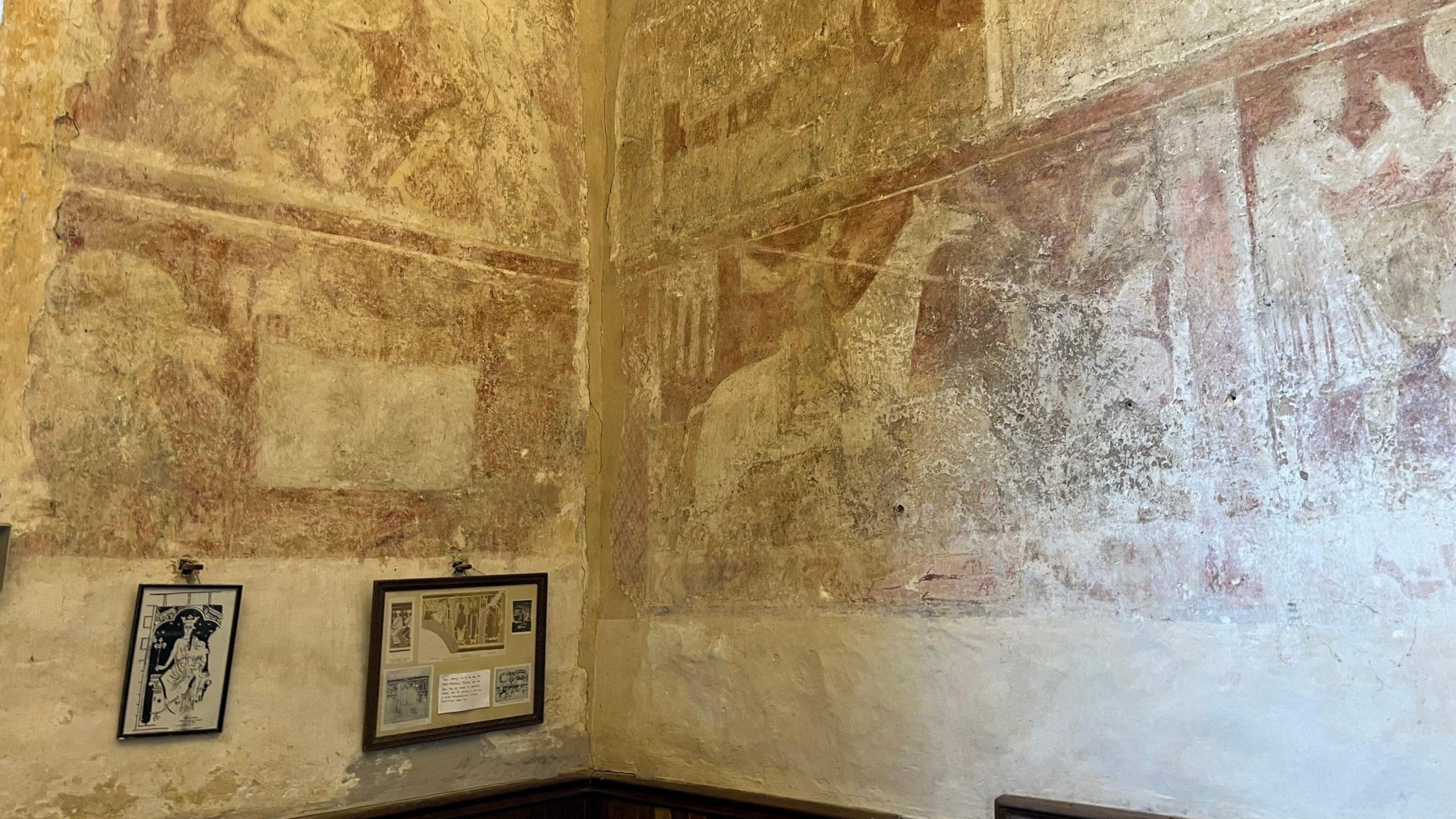 A faded image of St George riding a horse holding a spear on the church walls. The painting is a brown colour 