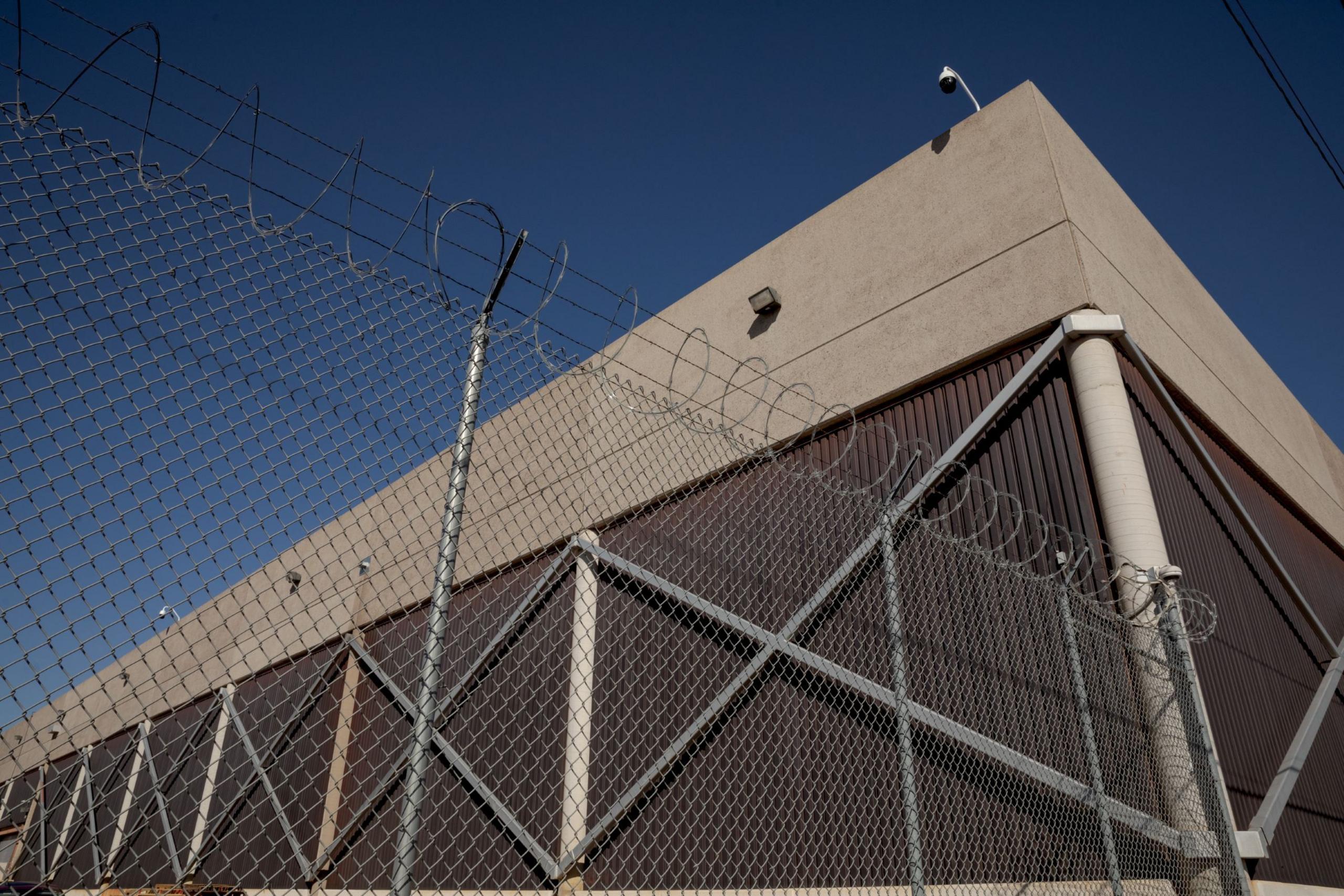 Razor wire sits atop a fence outside the Maricopa County tabulation centre. Multiple security cameras can be seen on top of the building. 