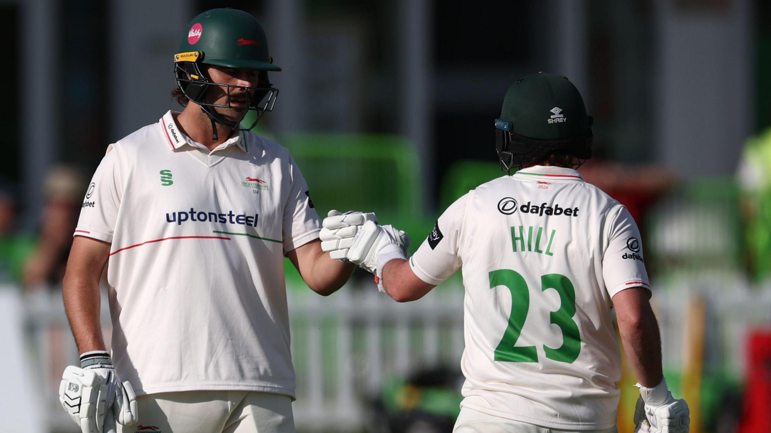 Lewis Hill with HILL 23 in green letters on the back of his white shirt punches gloves with Ben Green (left)