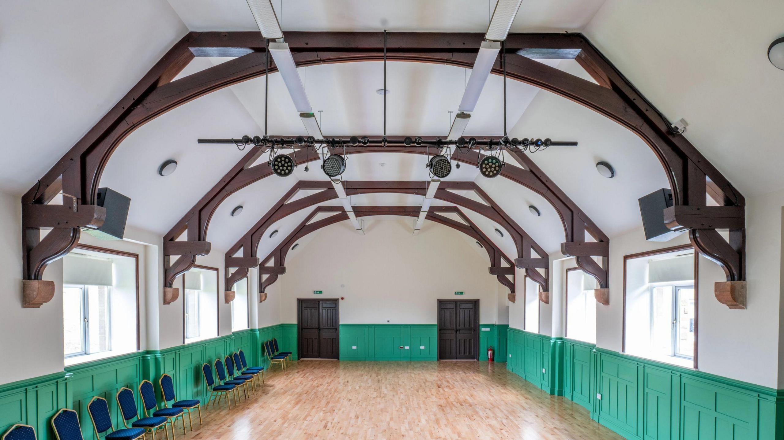 The finished inside main auditorium at Skelton Toppin Memorial Hall. It has a new wooden floor, mint green painted wall panelling, white ceiling and natural coloured wooden roof supporting