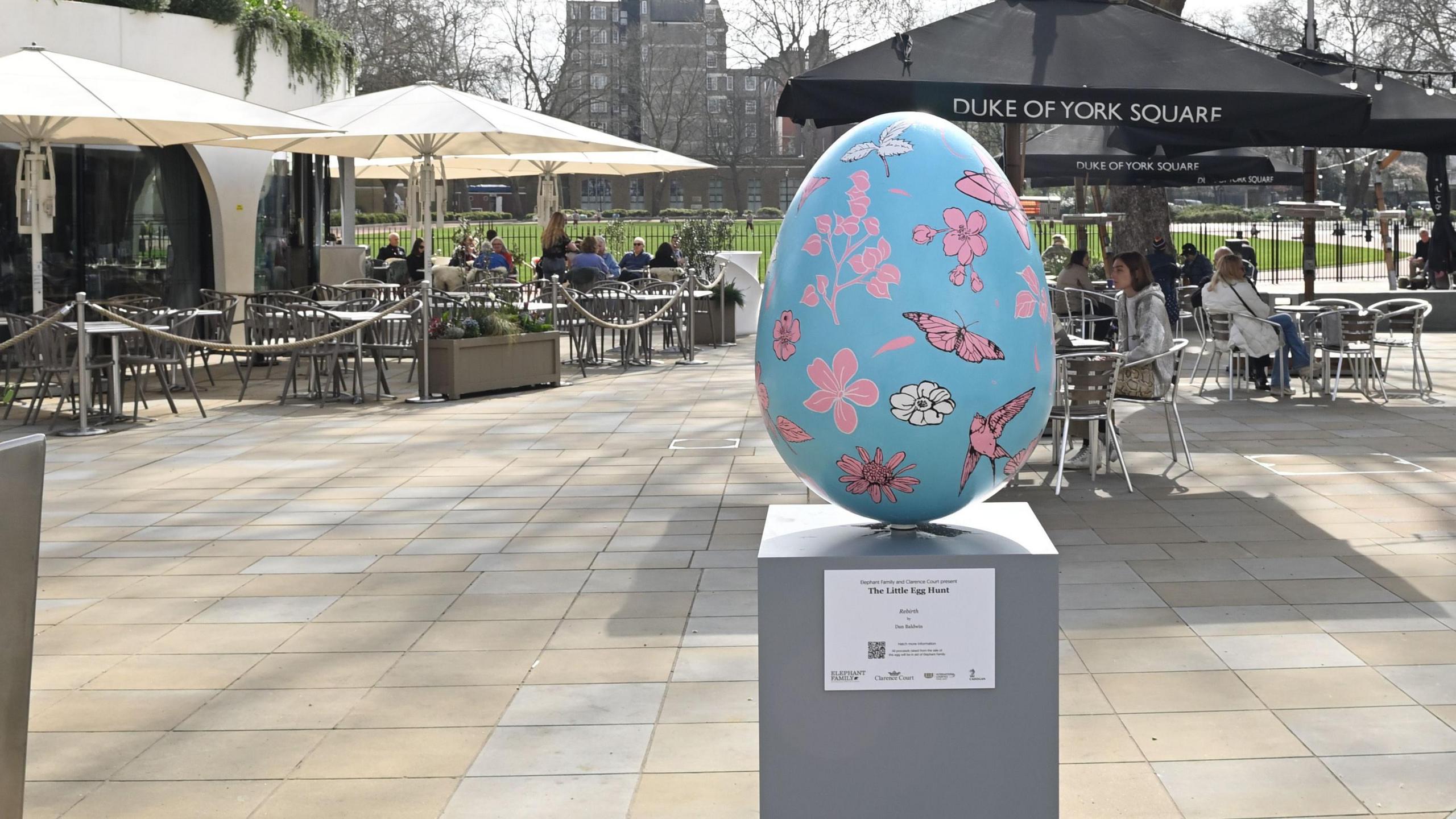 A blue egg with pink and white flowers and pink butterflies and birds in Duke of York Square.