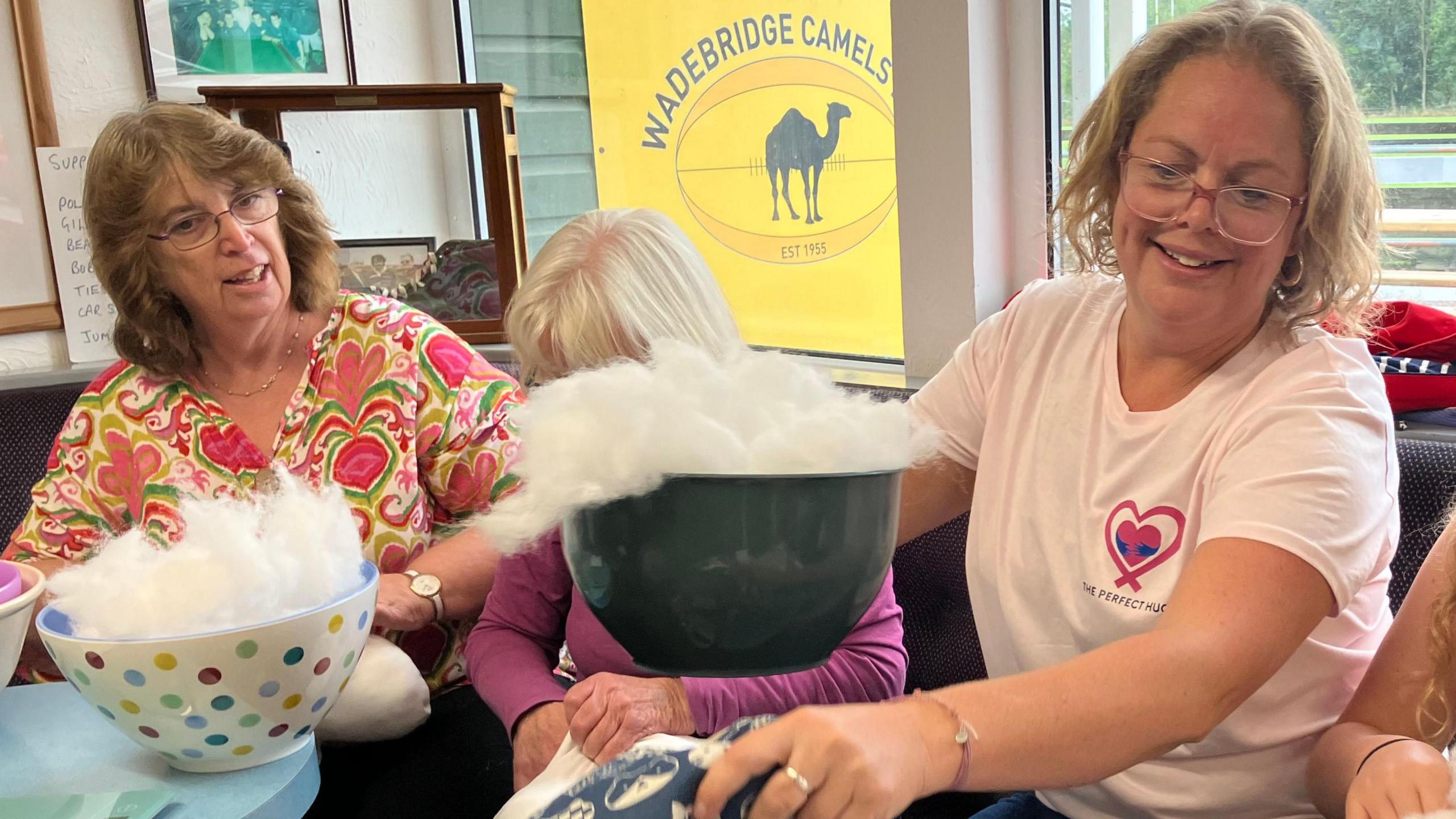 Chevi Mcilroy and volunteers sat down, putting patterned cushion covers into heart-shaped cushions.