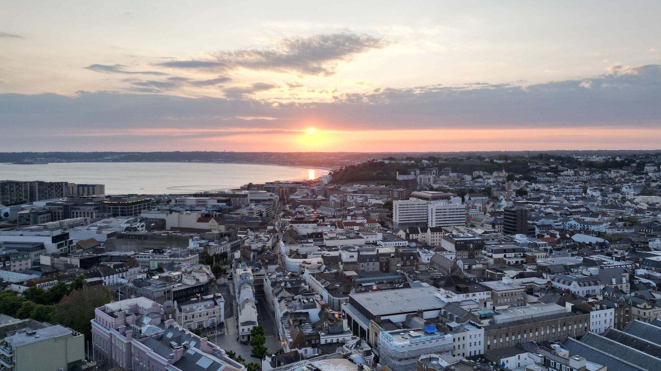 The sun sets over St Helier in this aerial photo. The bay is in the distance beyond which is a curved shoreline.
