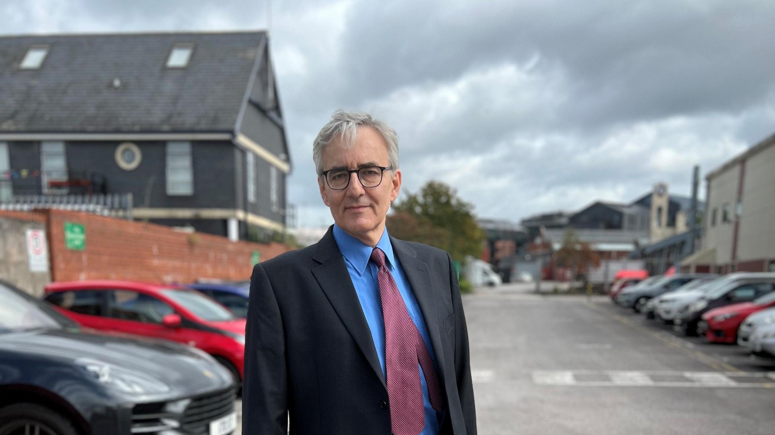 Andrew Varga in the car park of his business, wearing a smart suit. 