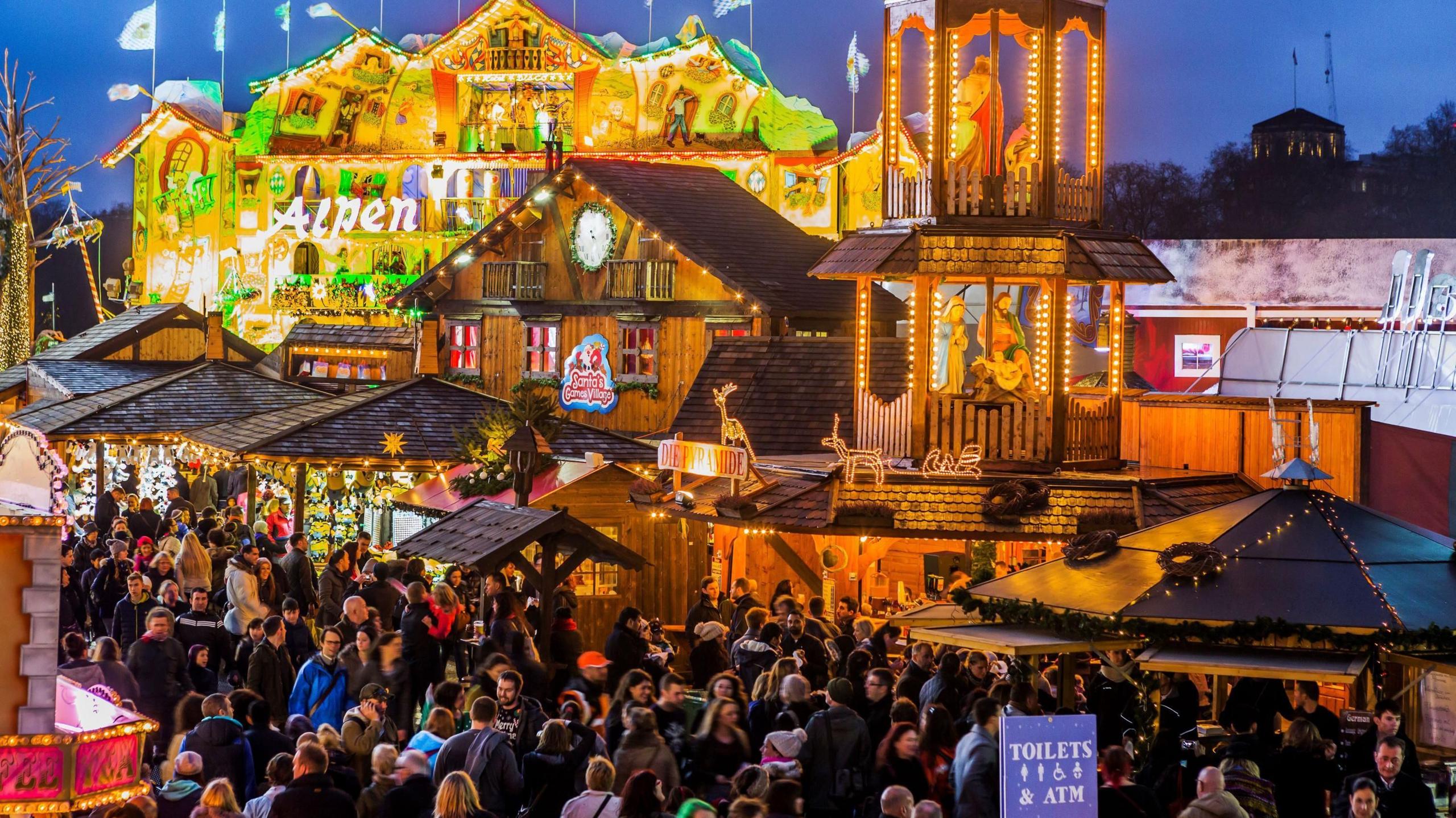 Alpine-style bars with crowds of people standing around at Winter Wonderland