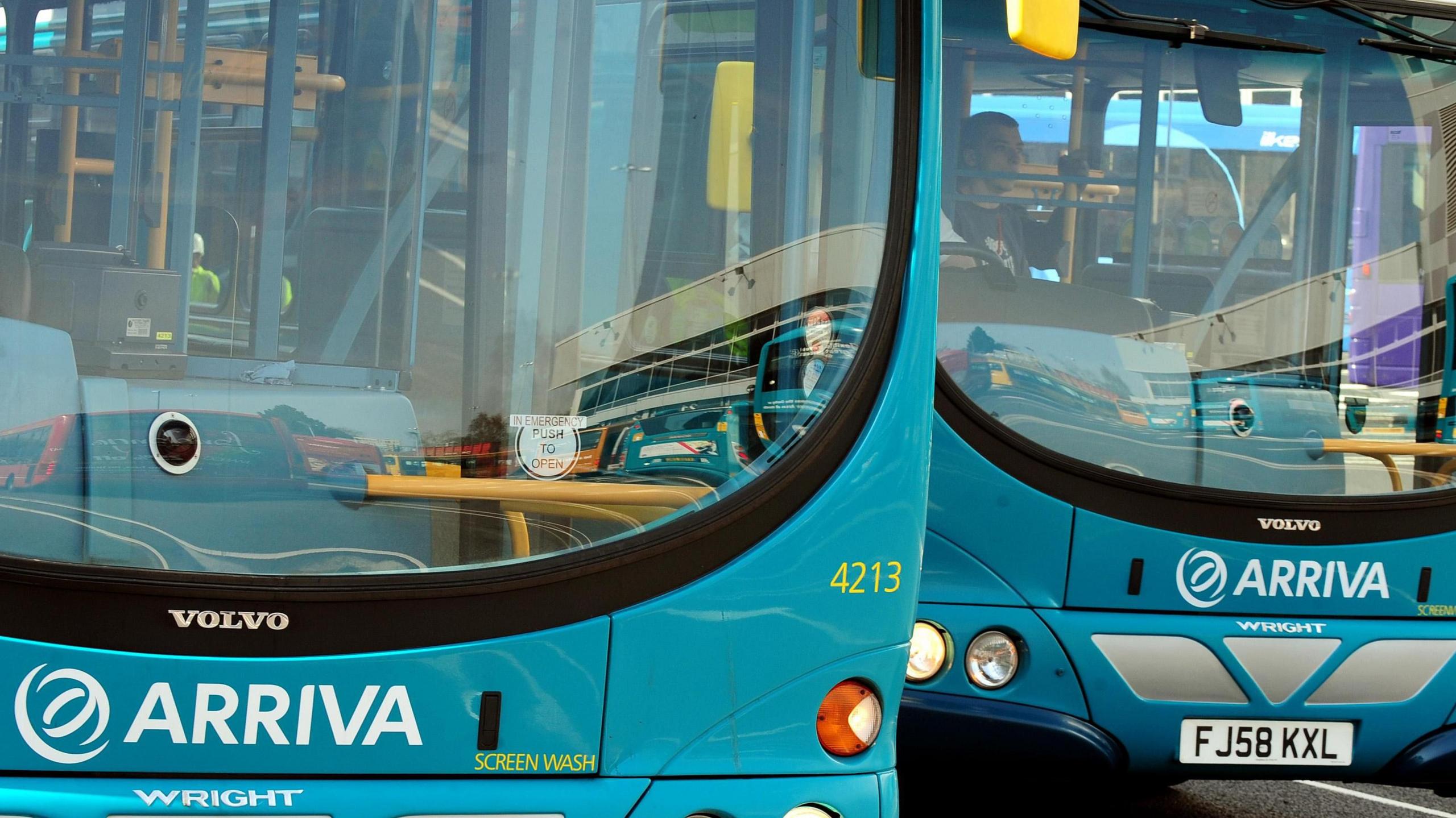 Two blue-coloured Arriva buses parked at a bus depot.