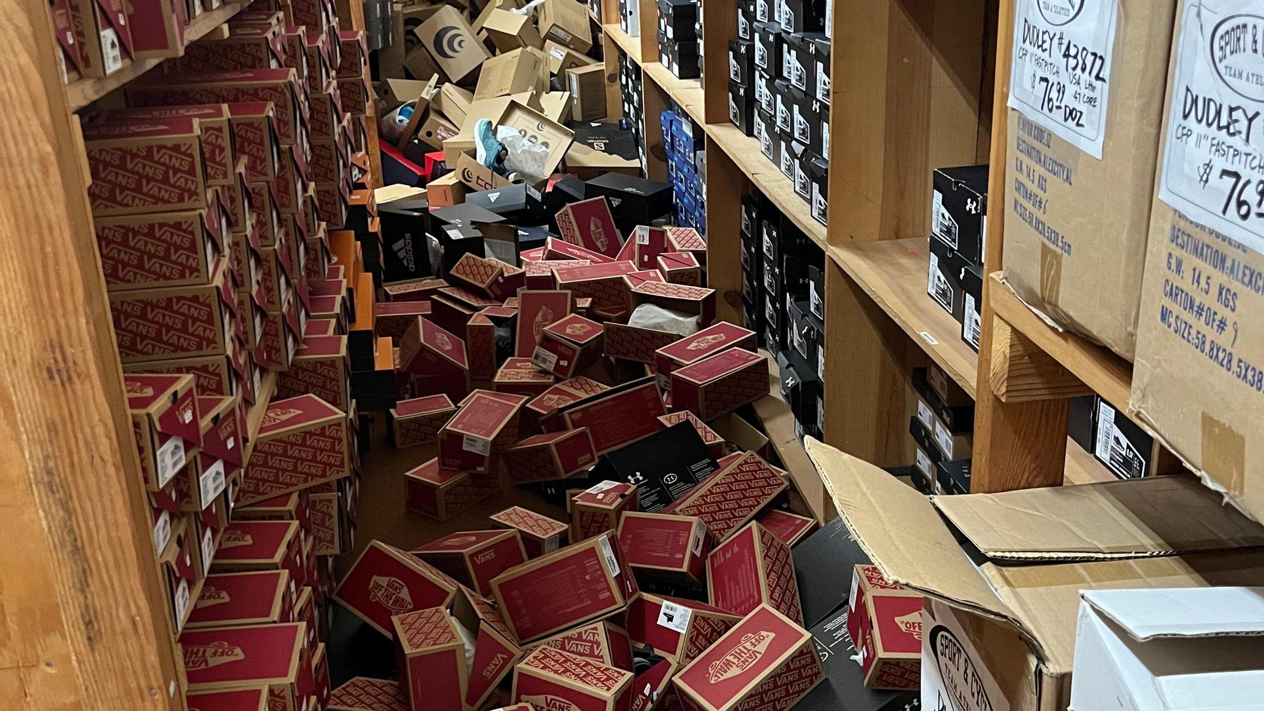 Shoe boxes strewn on the floor between two shelves in a sportswear store.