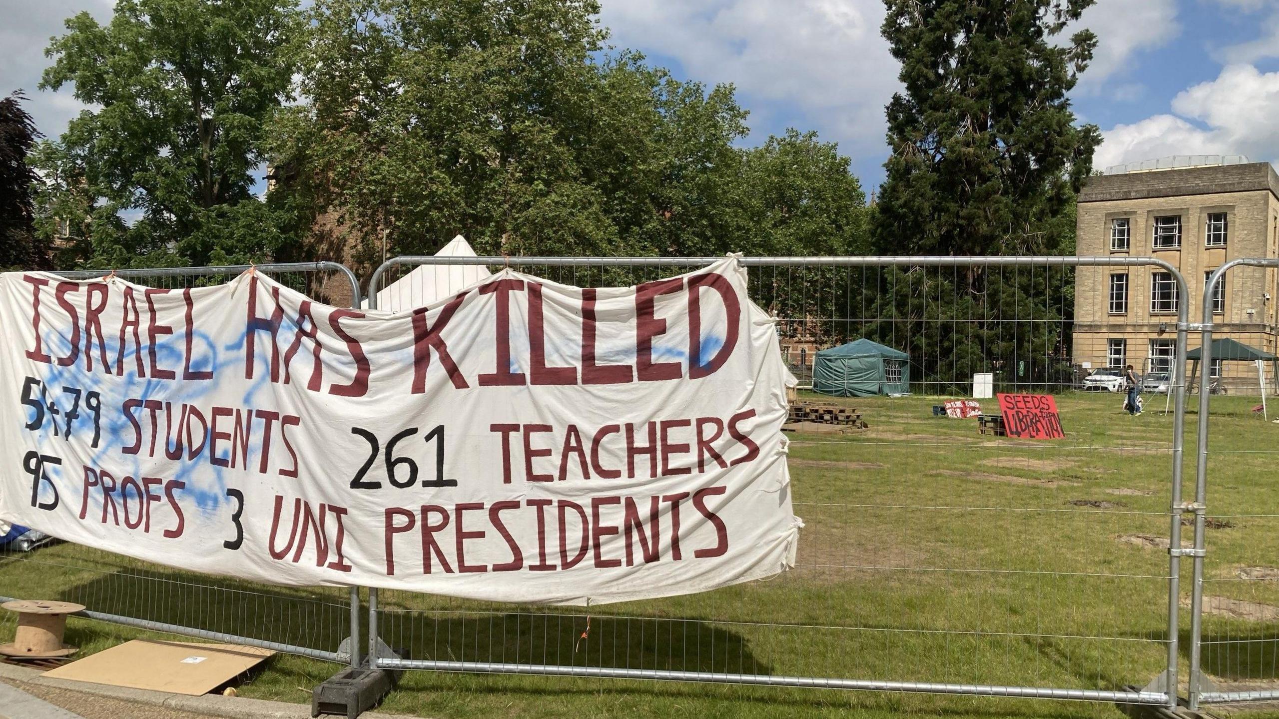 Fencing around protest encampment with banner stating that students, teachers, professors and university presidents have died in Gaza