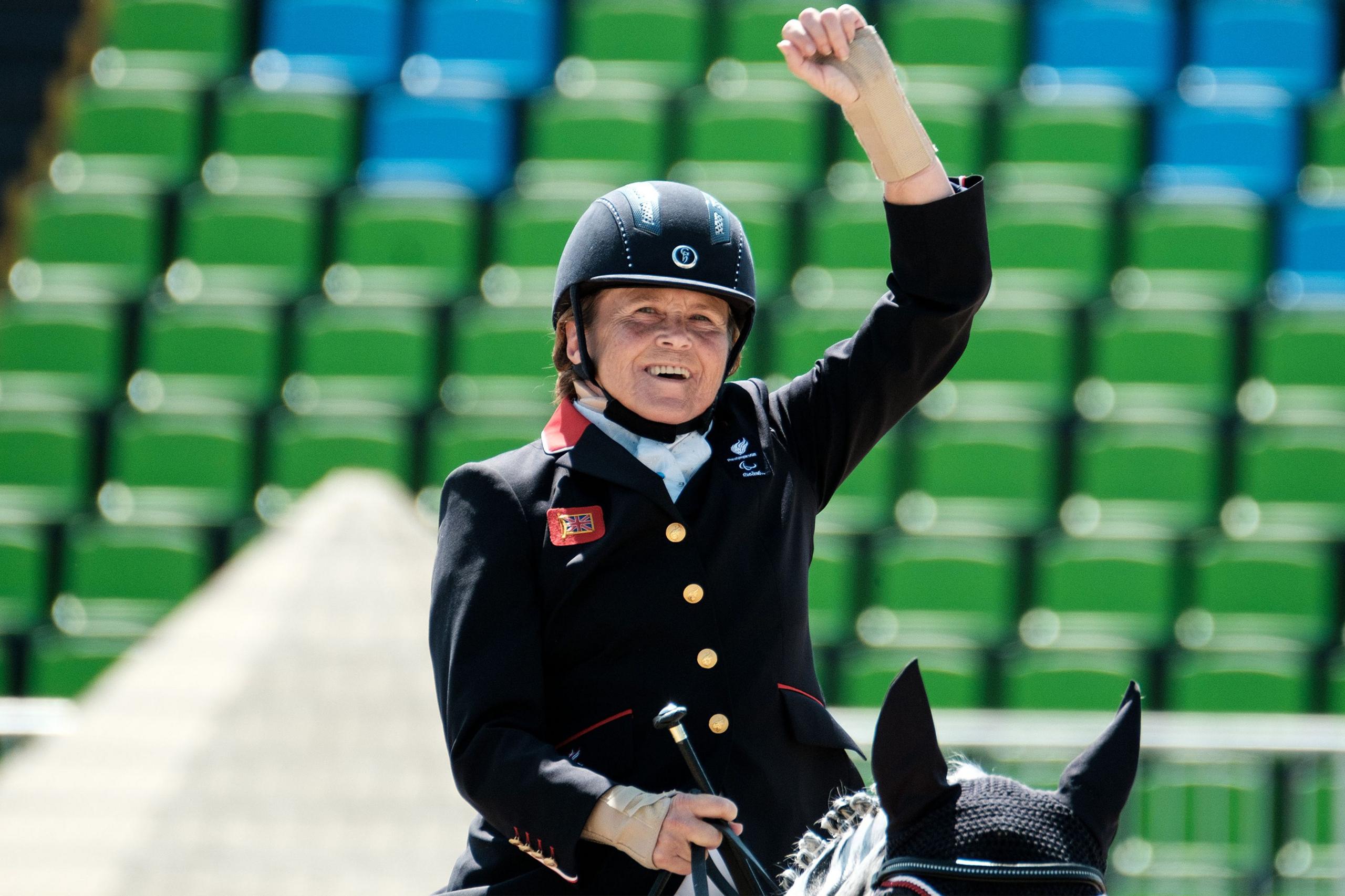 Anne Dunham po hipën mbi një kalë në një arenë, e veshur me një xhaketë të zezë kalërimi me kopsa të arta, një këmishë të bardhë dhe një helmetë të zezë. Krahu i djathtë i kalorësit është ngritur në një gjest festiv, duke mbajtur një kapelë kalërimi në dorën e majtë. Kali është pjesërisht i dukshëm, me një kapuç të zi në vesh. Sfondi tregon rreshta me ndenjëse të gjelbra dhe blu në stadium, që tregojnë një mjedis garues.