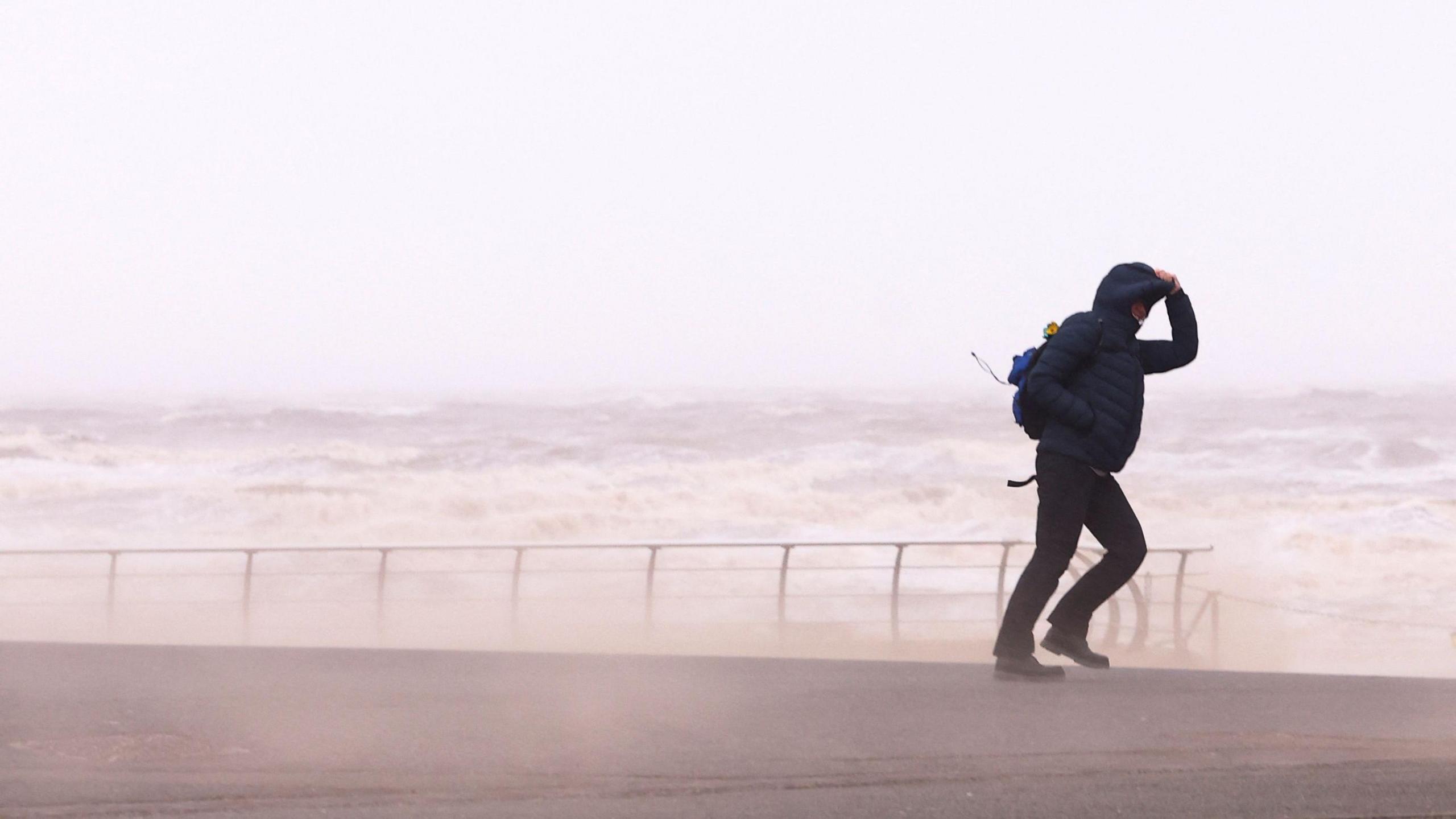 Person walking against strong wind near a beach in Blackpool on 7 December