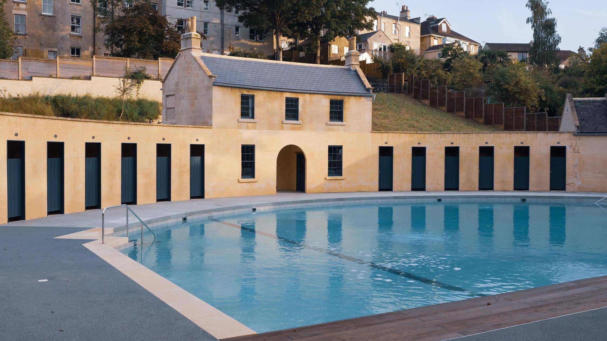 Empty lido with honey-stone buildings in background