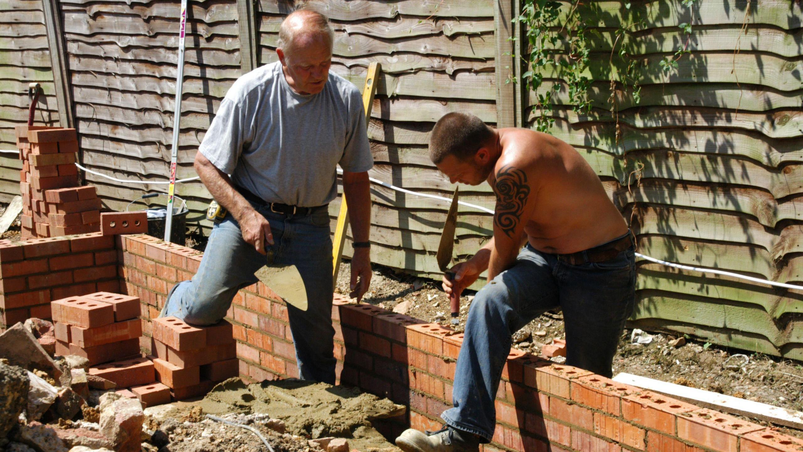 Two builders laying bricks on a new property