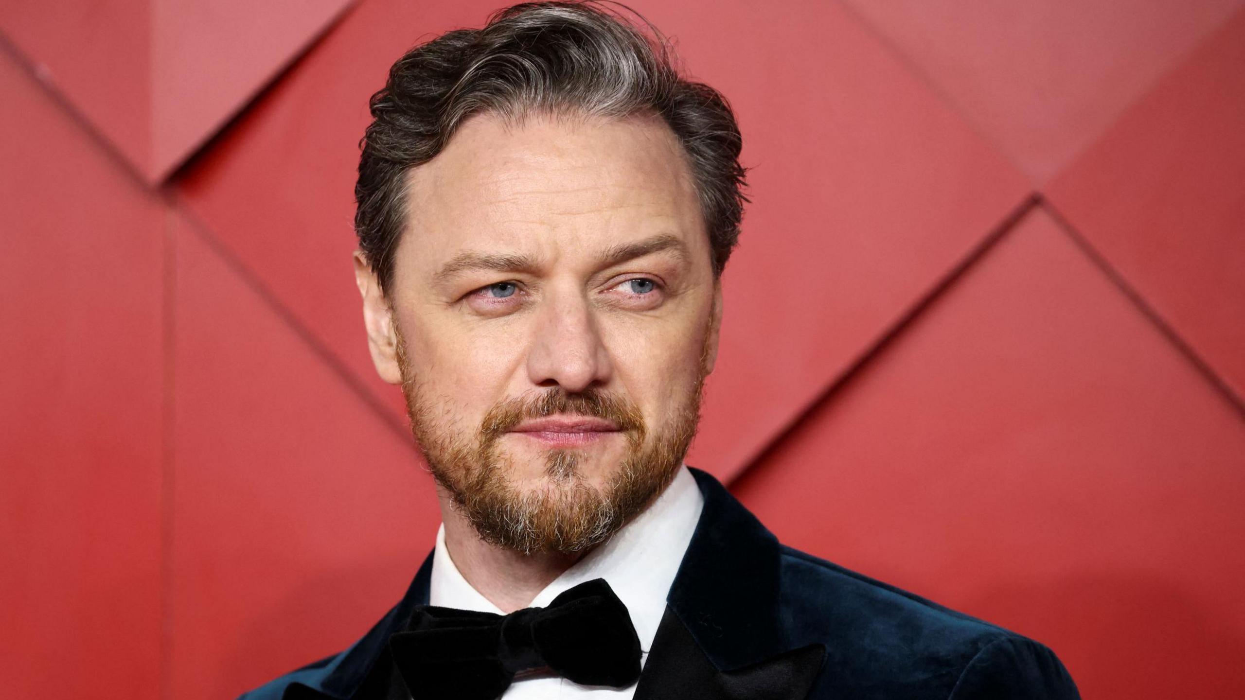 James McAvoy on the red carpet at a film event - he is wearing a suit with tie, and has a moustache and beard.