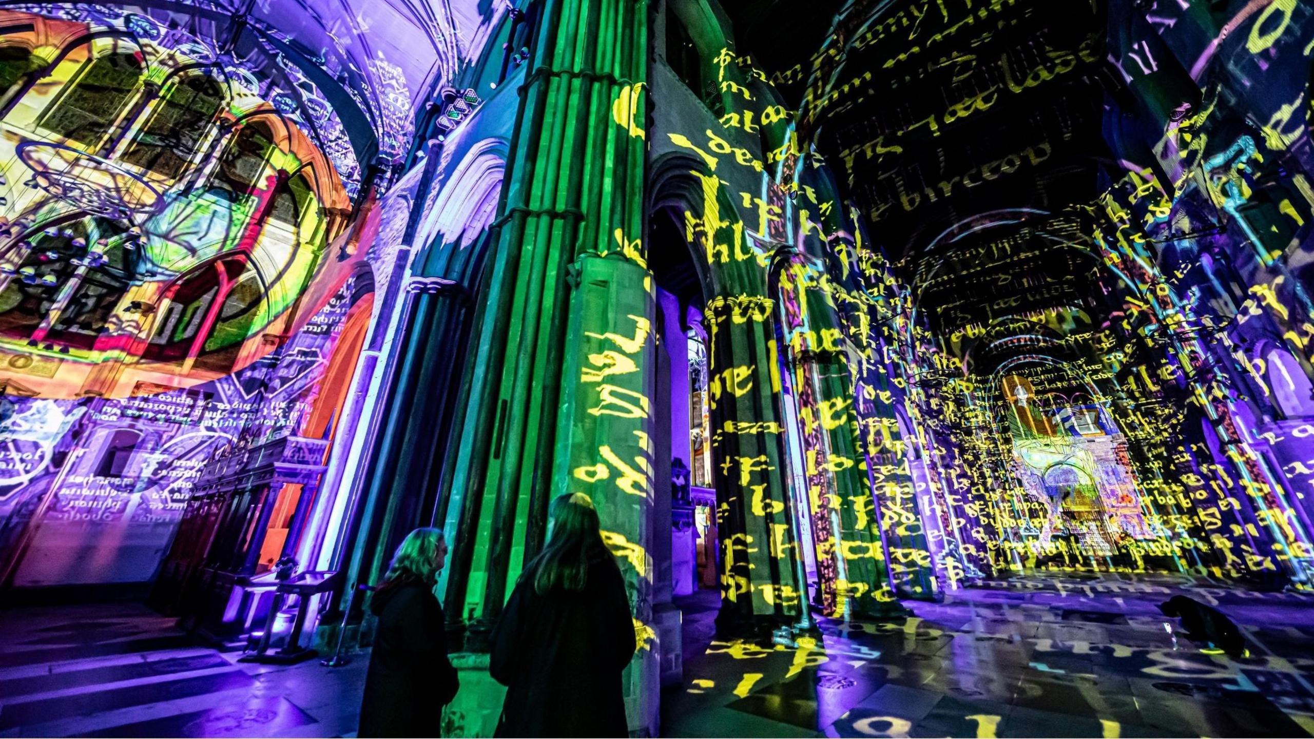 Text and lighting is projected across the inside of a church.