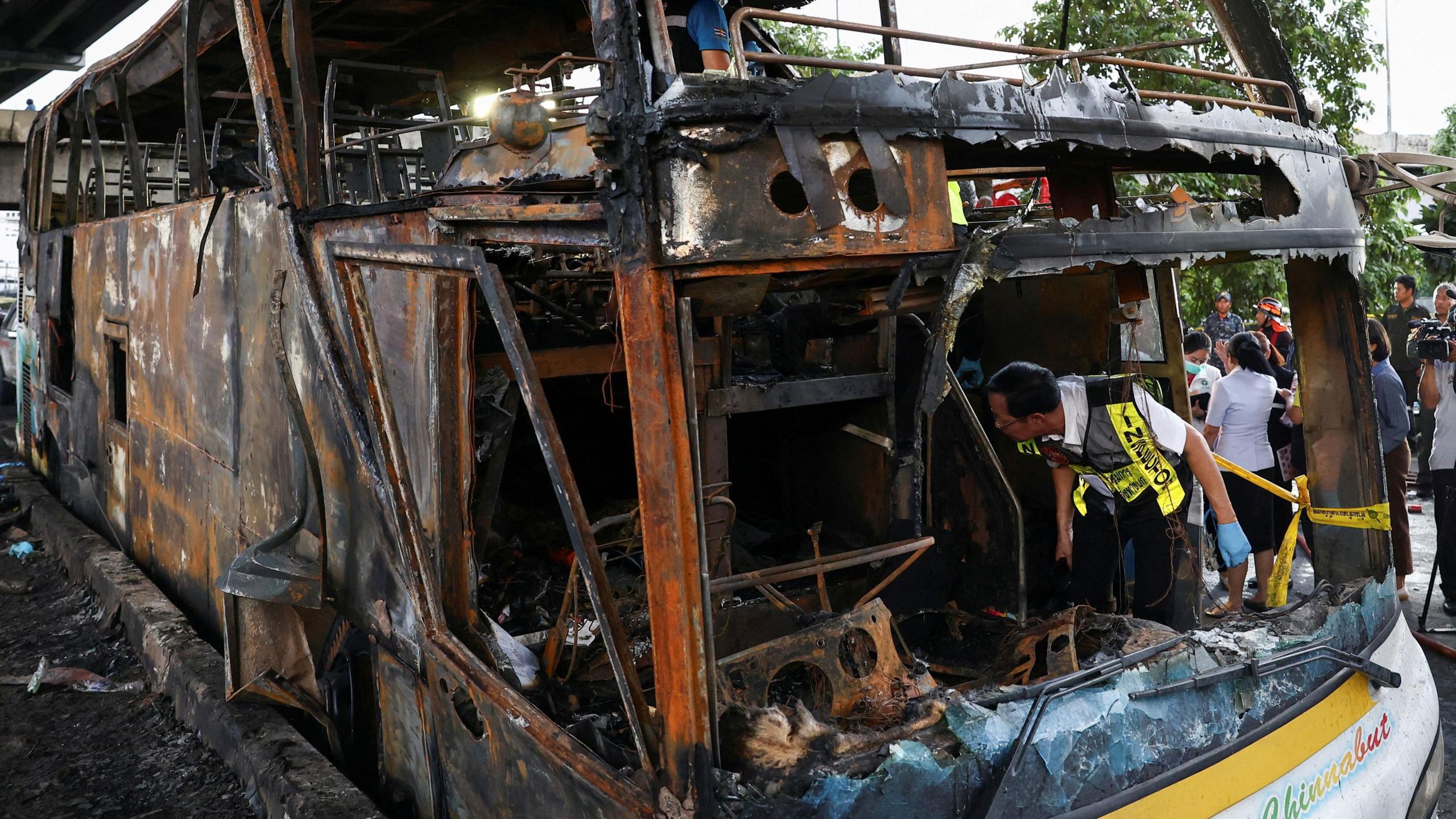 Inspectors work inside a burnt-out bus that caught fire while carrying teachers and students from Wat Khao Phraya school, reportedly killing and injuring dozens, on the outskirts of Bangkok, Thailand, October 1, 2024. 