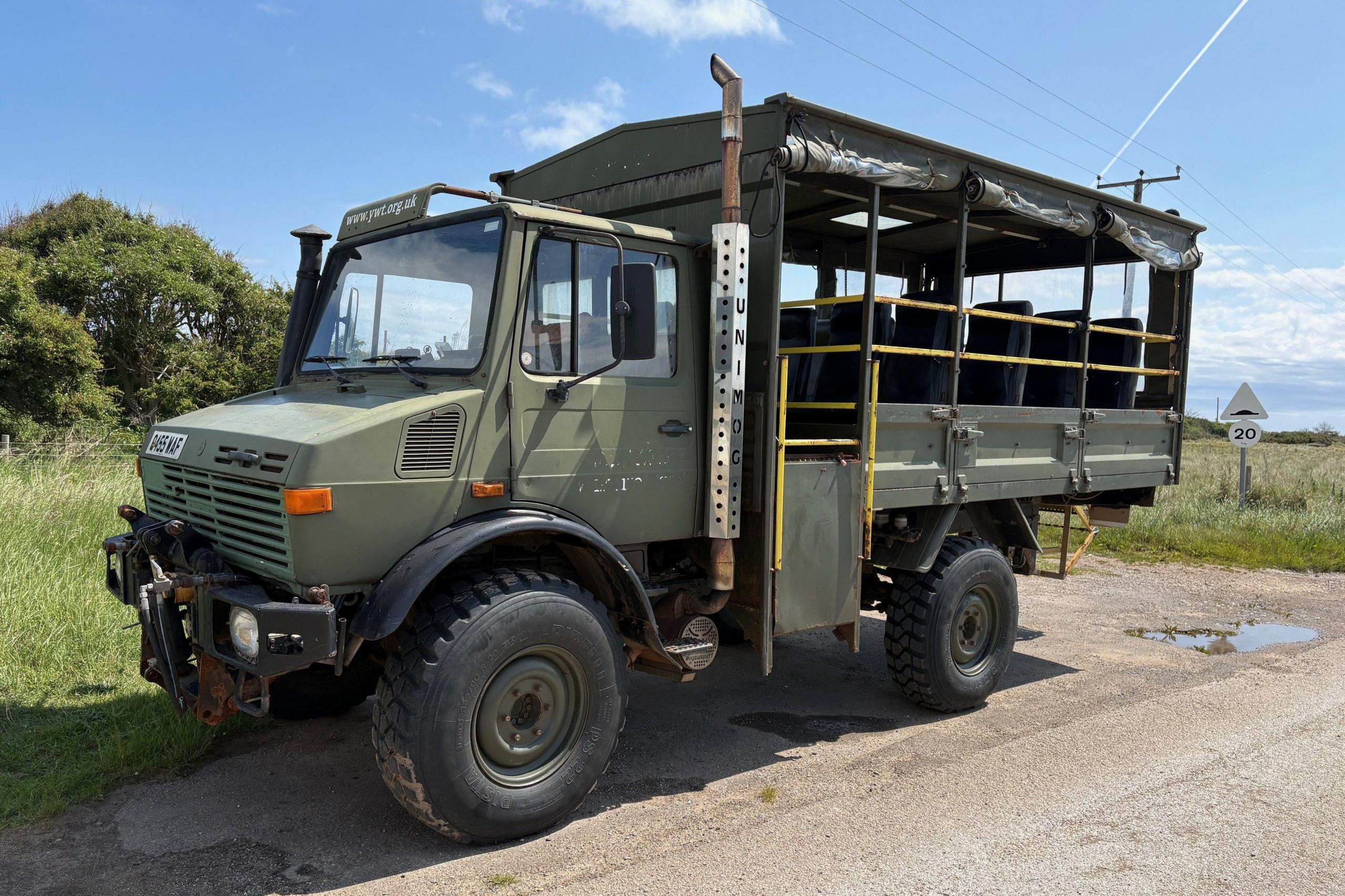 A green Army vehicle with seating for 10 passengers in the rear. It has the word UNIMOG written down the side.
