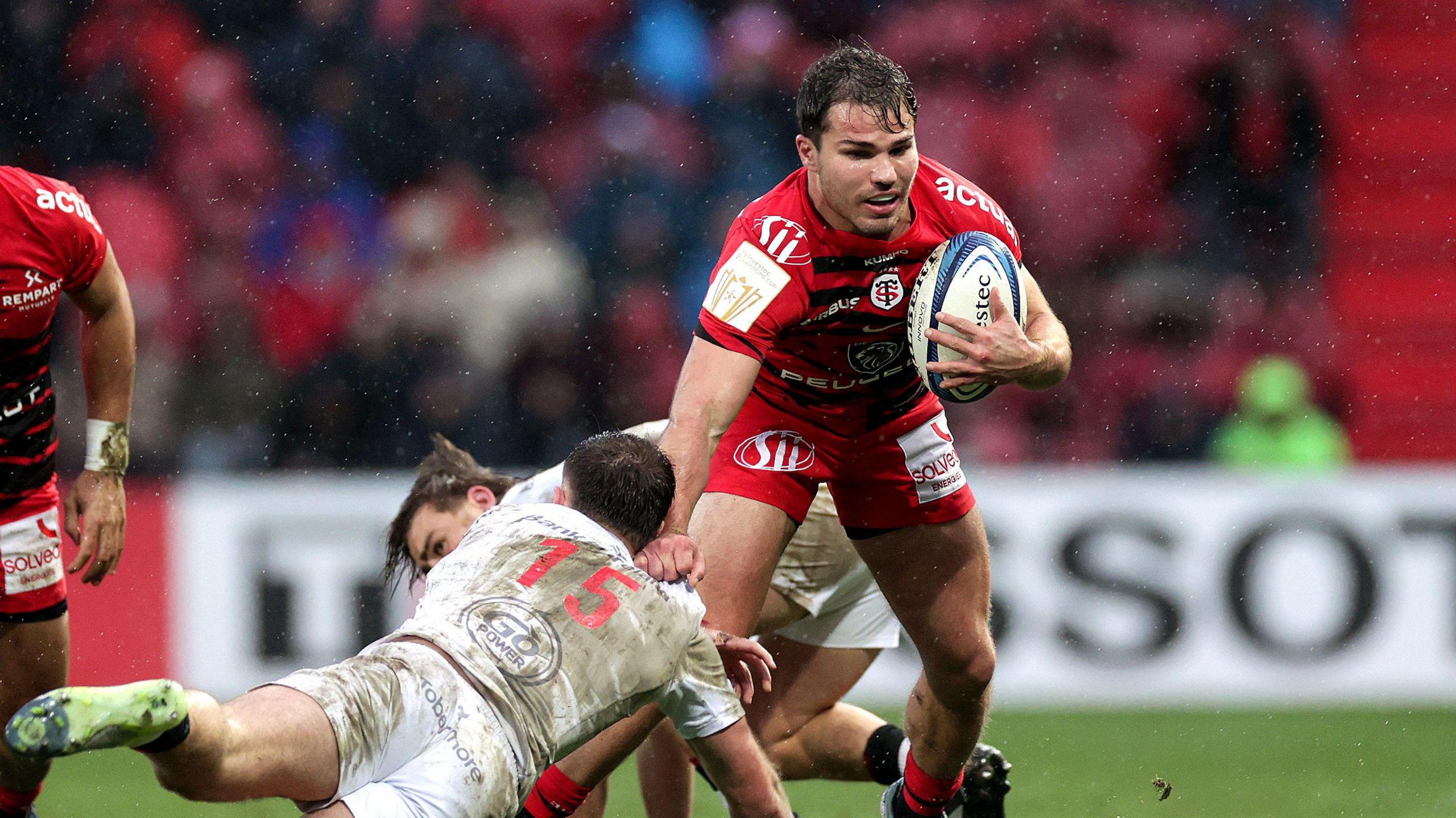 Antoine Dupont fends off a tackle