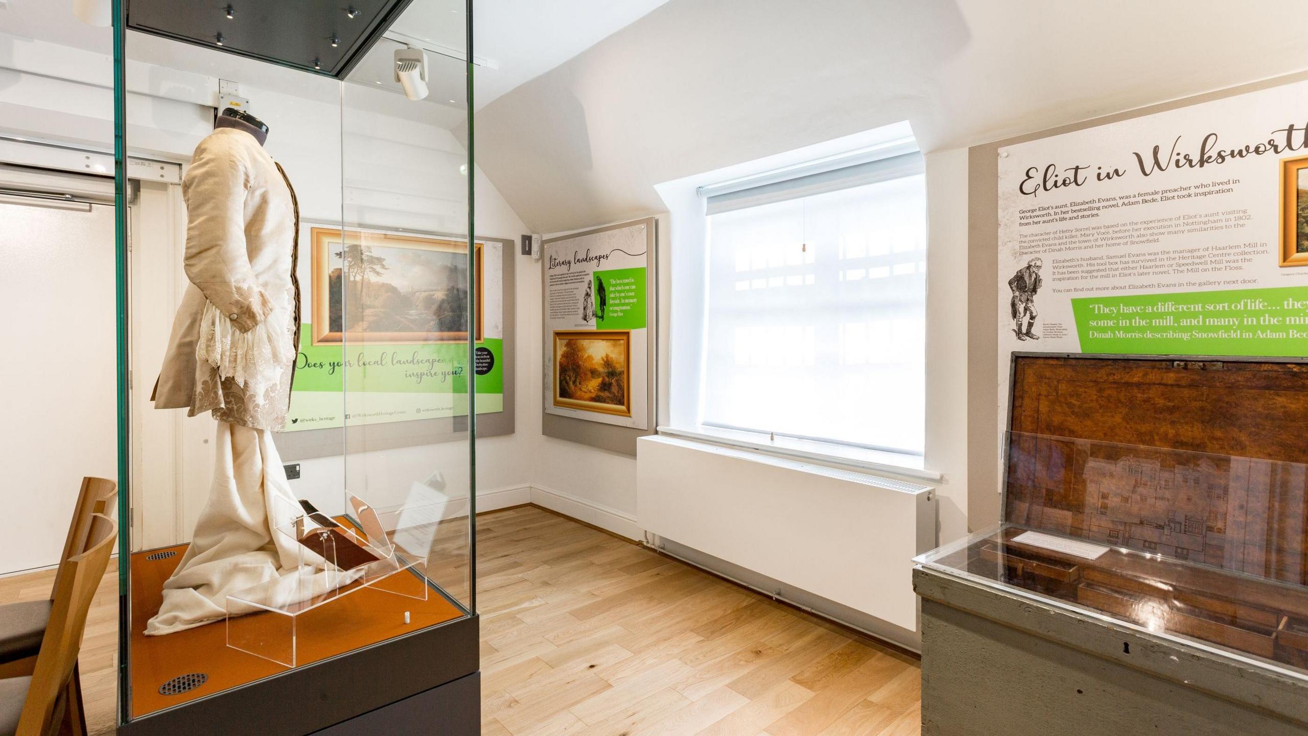 An exhibition inside Wirksworth Heritage Centre. There is a glass cabinet on the left with an outfit inside and signs on the wall with information on. 