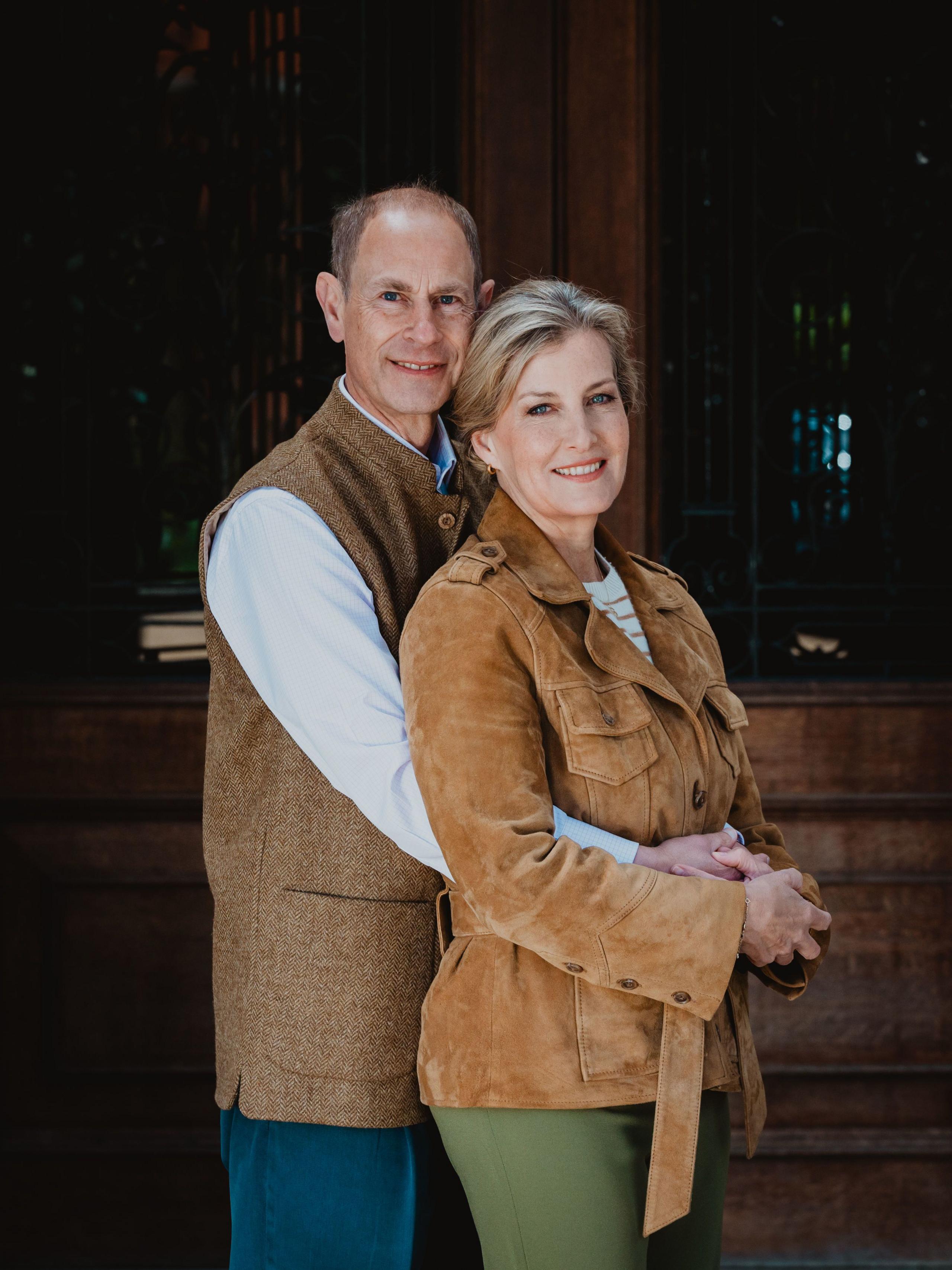 The Duke of Edinburgh stands behind his wife, the Duchess of Edinburgh, with his arms around her in a portrait